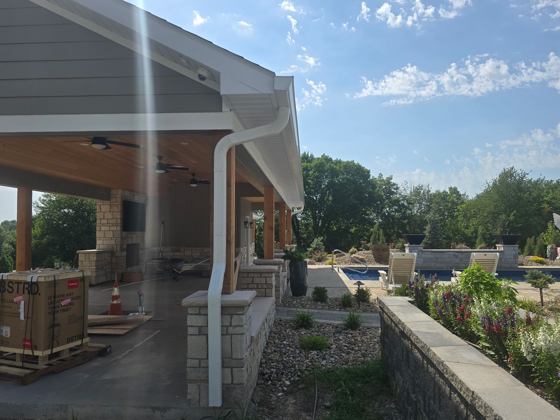 Covered porch with white columns beside a garden bed and patio in bright sunlight
