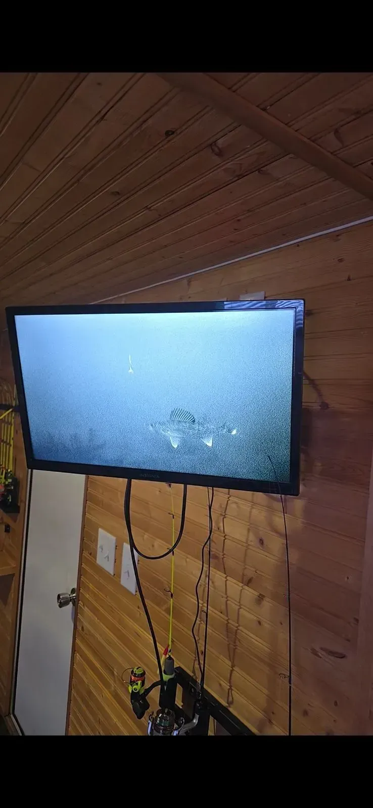 Flat-screen TV mounted on a wooden wall in a slanted attic room, showing a blank blue screen.
