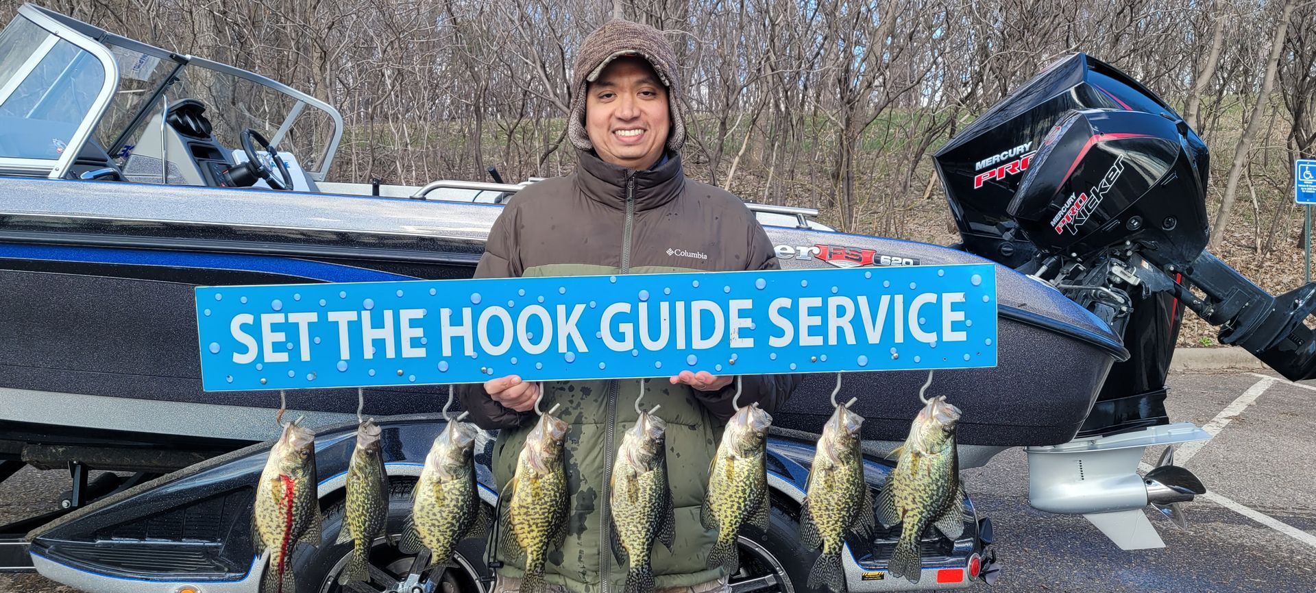 Outdoor fishing setup with a person behind a row of fish and a blue banner reading “SET THE HOOK GUIDE SERVICE”