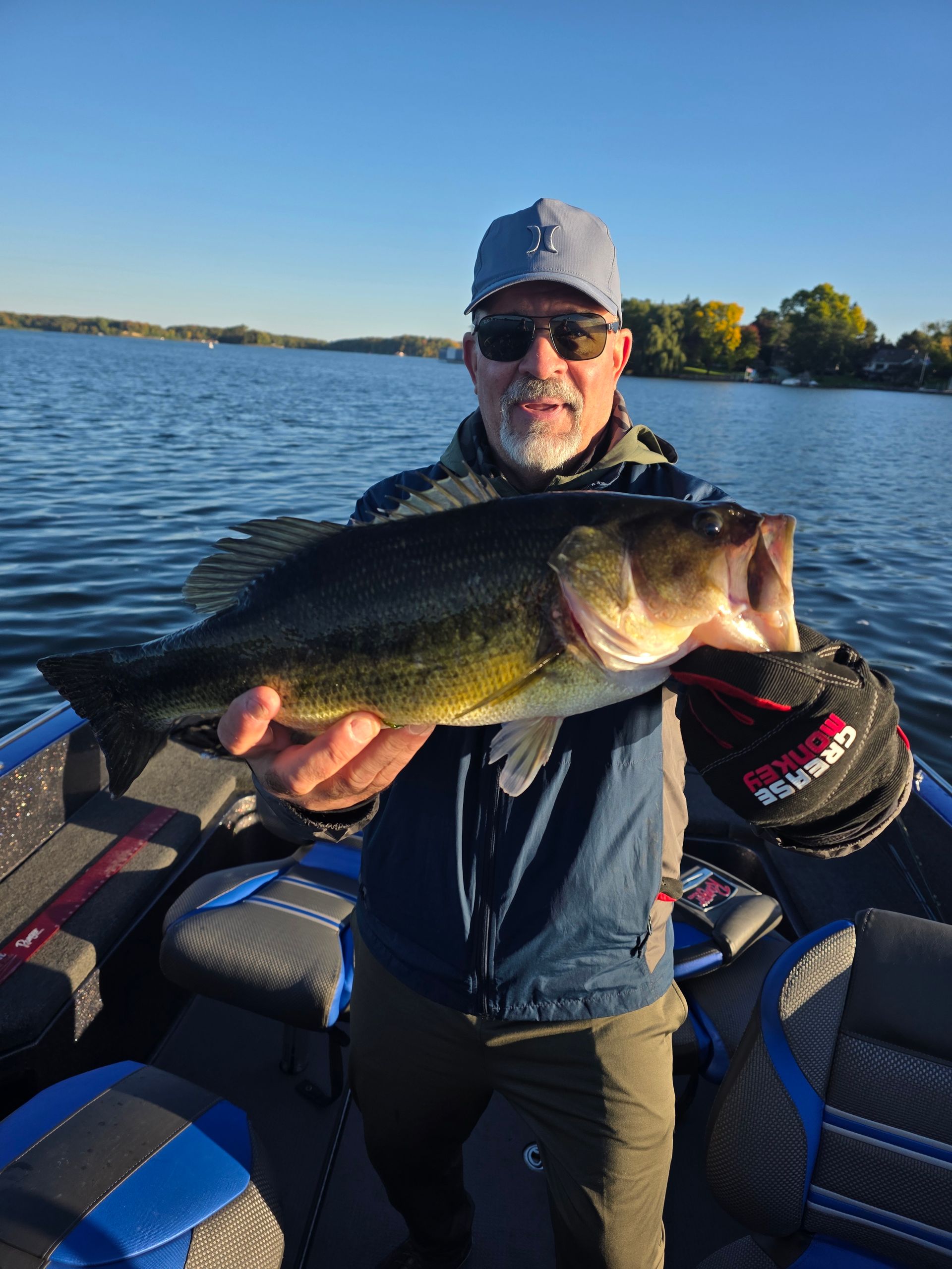 Angler on a boat holding a large bass on a sunny lake