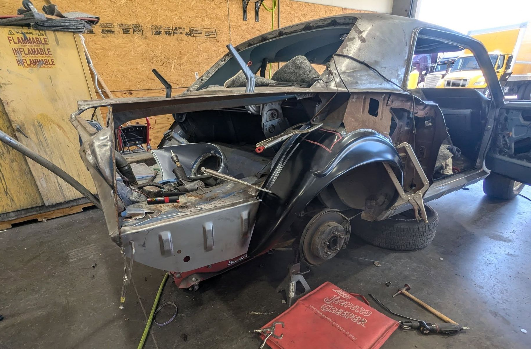 A partially disassembled black car in a workshop, undergoing restoration.