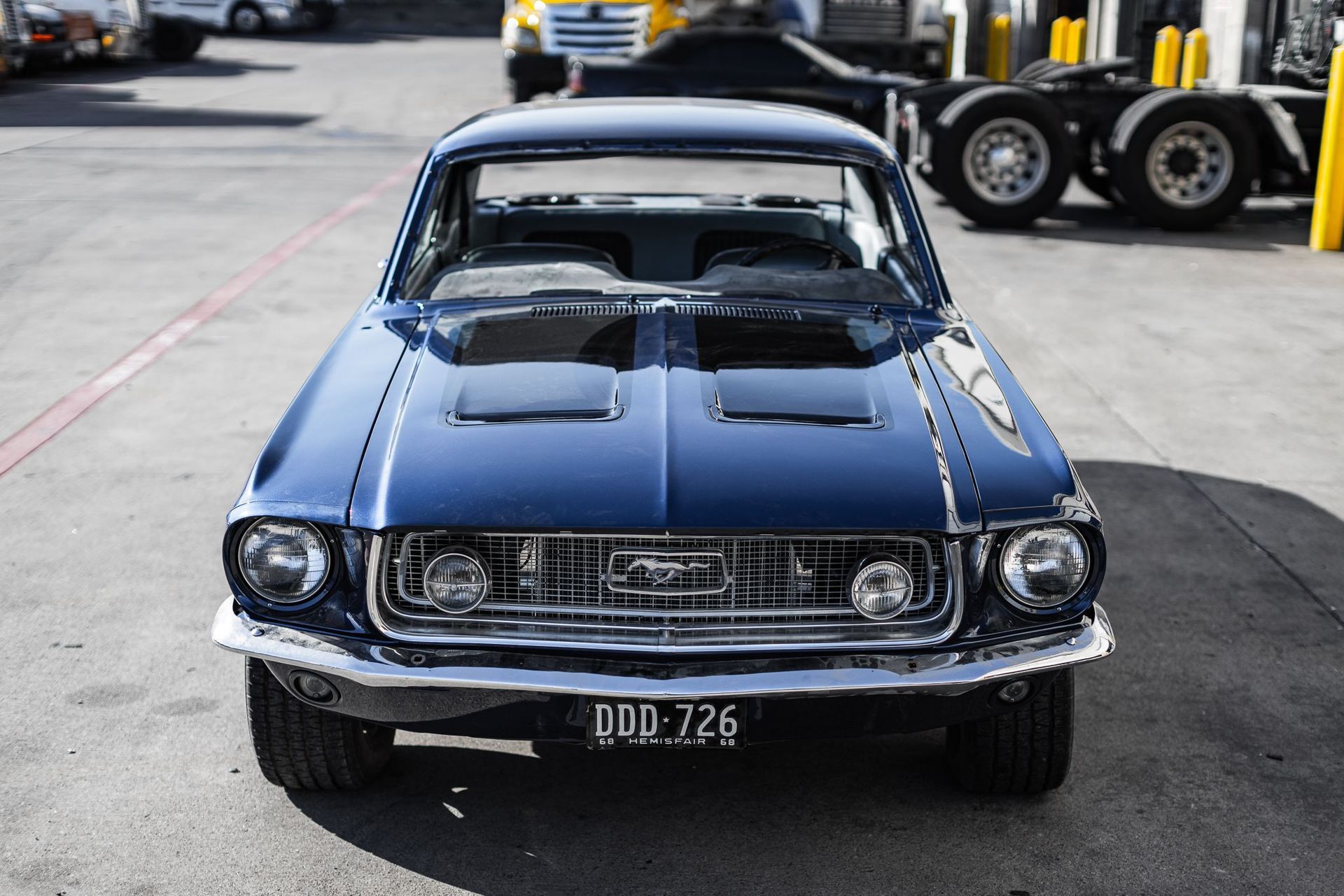Blue classic Ford Mustang, front view, outdoors in parking area.