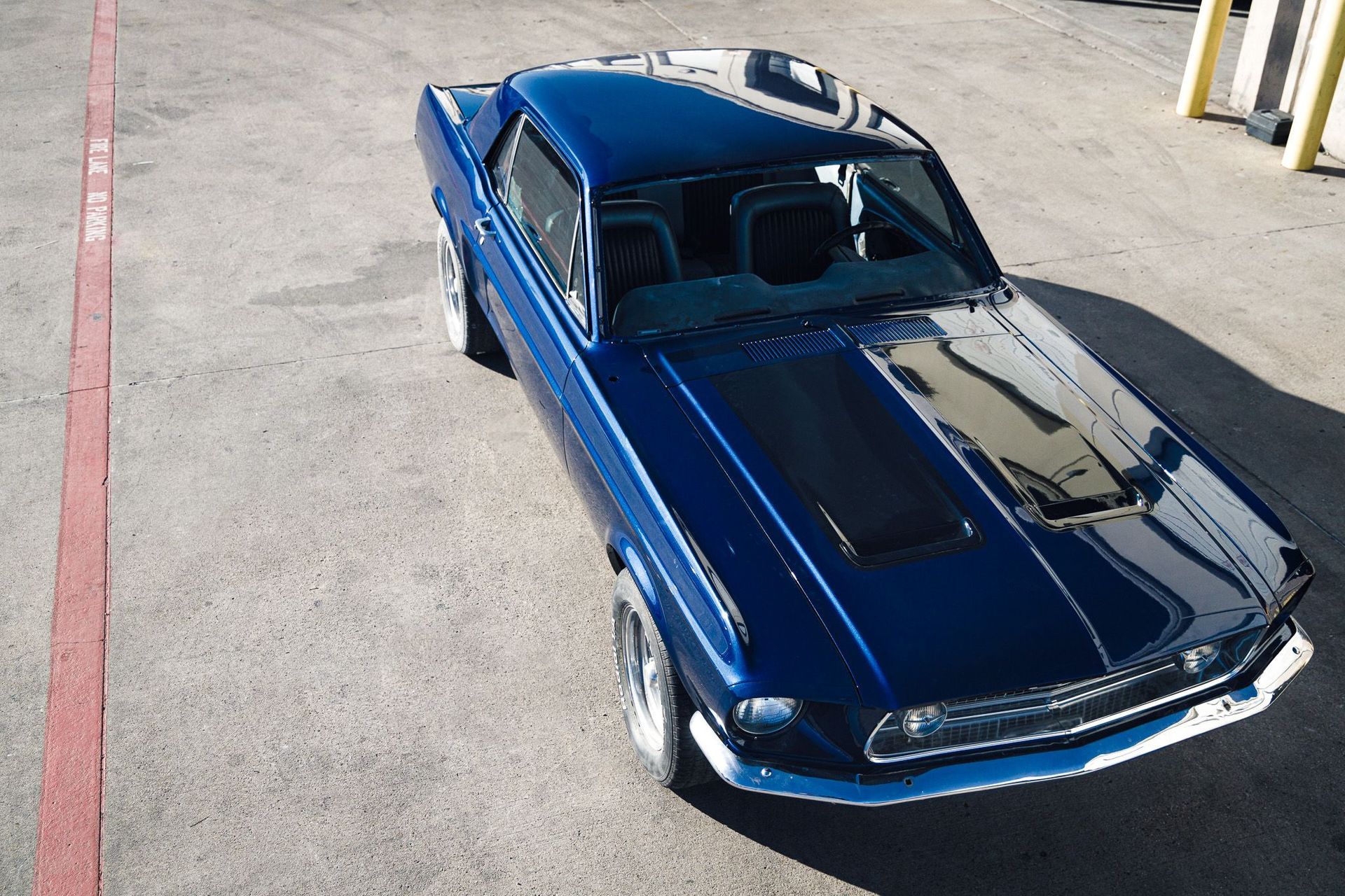 Blue 1969 Ford Mustang with black racing stripe parked on asphalt.