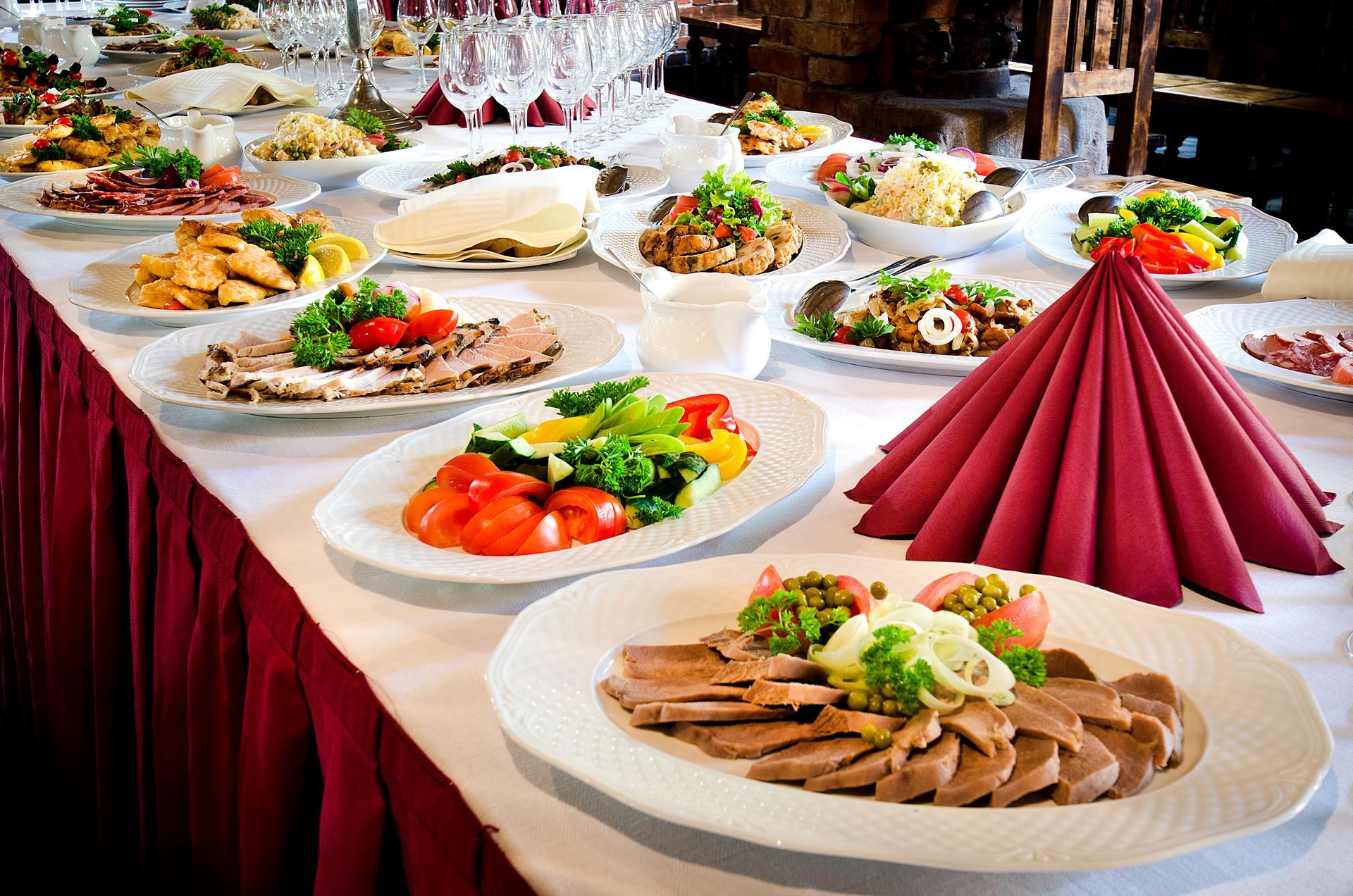 Buffet table with various dishes: salads, meats, and garnishes, in a restaurant setting.