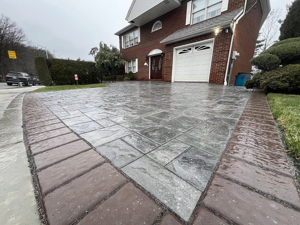 A brick driveway in front of a brick house with a garage door.