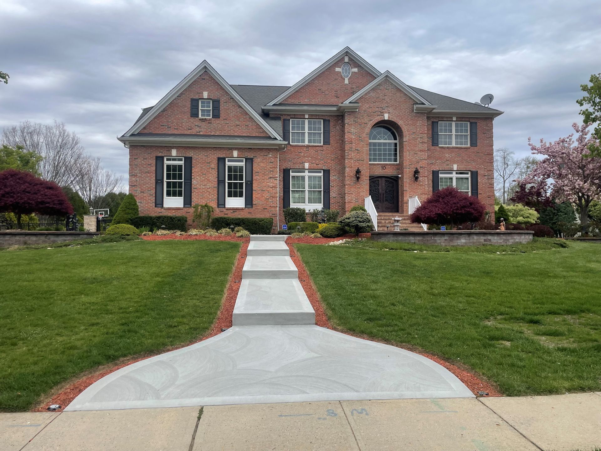 A large brick house with a concrete walkway leading to it.