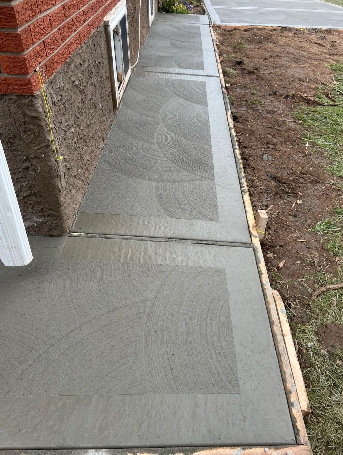A sidewalk is being built in front of a brick building.