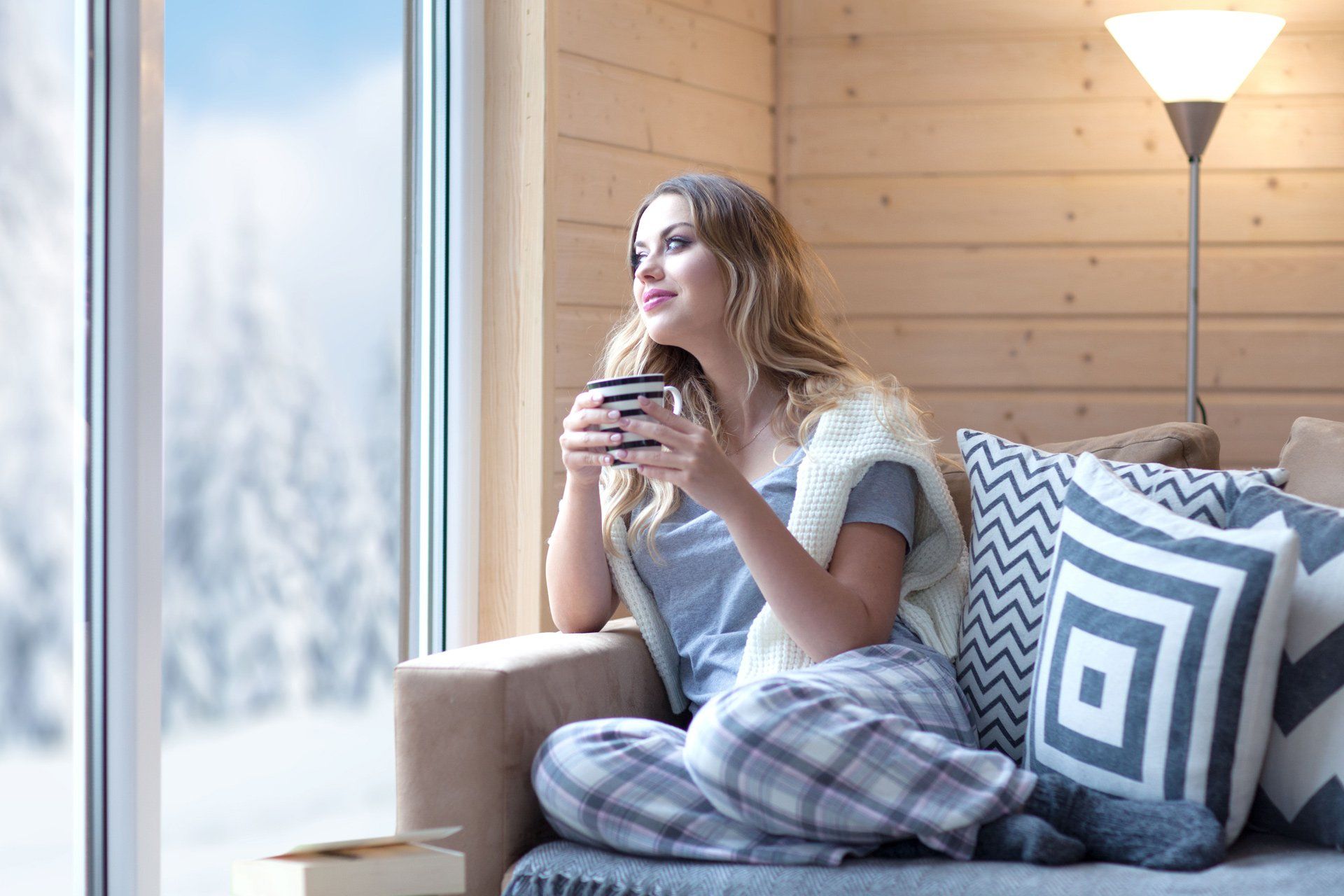 Young woman at home sitting on modern chair in front of window