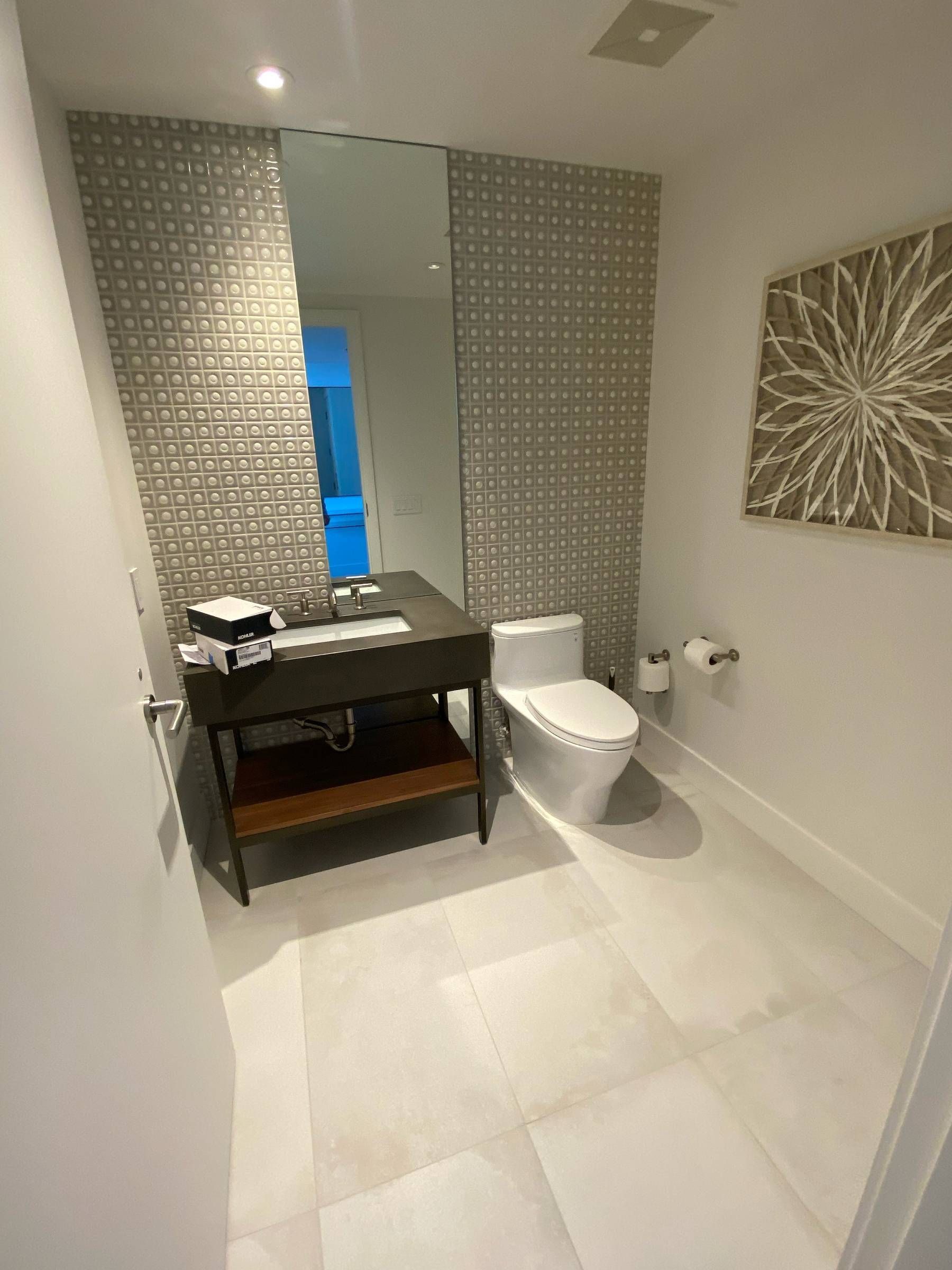 A bathroom with a toilet , sink and mirror.