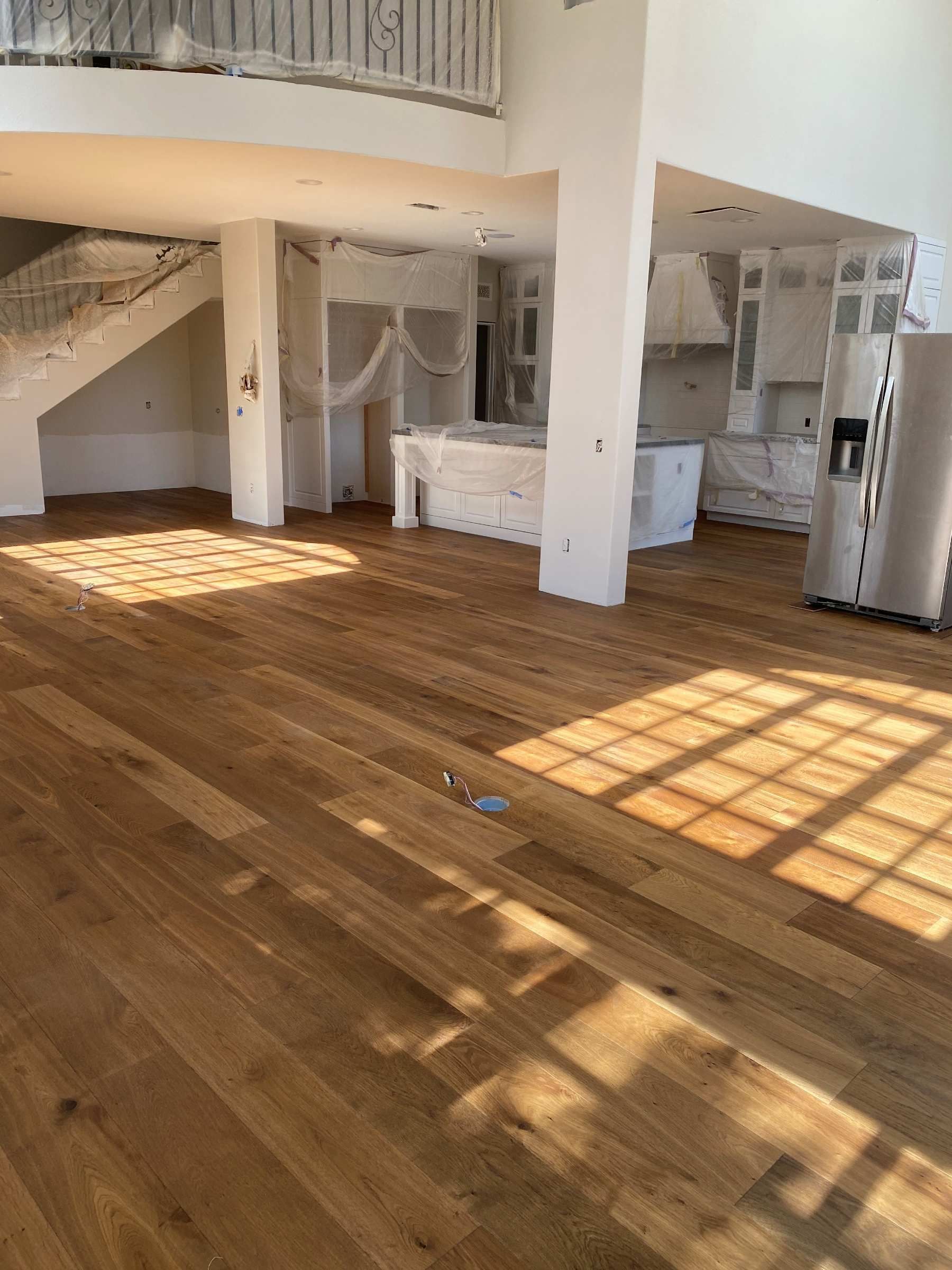 A large empty room with hardwood floors and a kitchen.