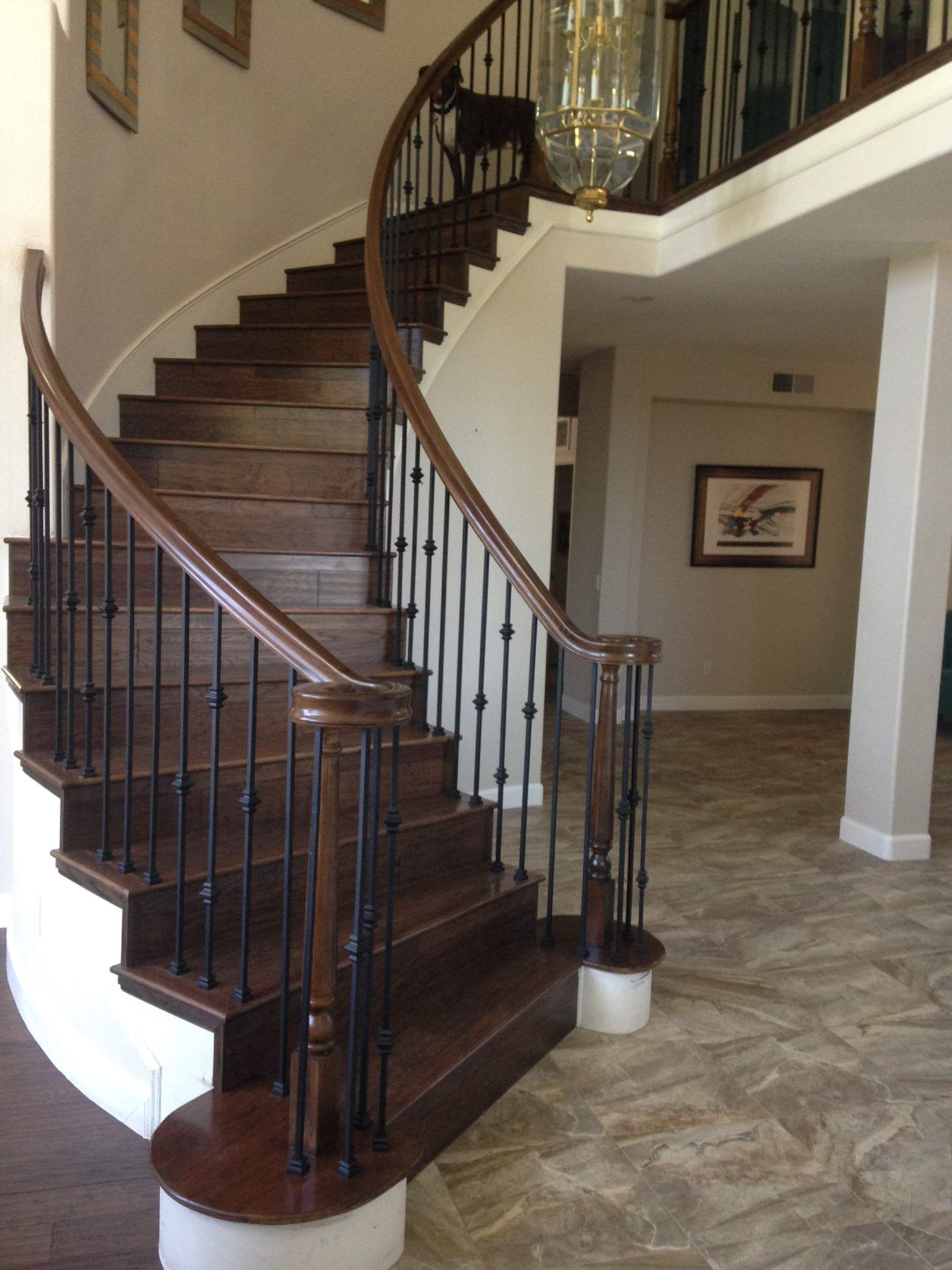 A curved wooden staircase with a black railing