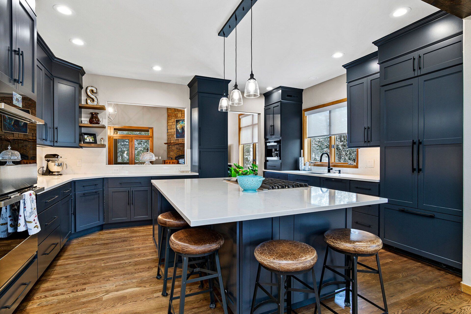 A kitchen with blue cabinets and a large island with stools.