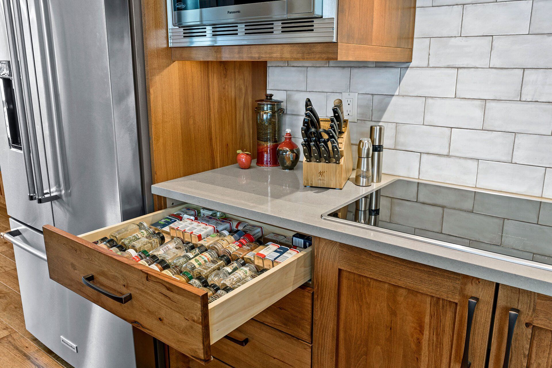 A kitchen with wooden cabinets , stainless steel appliances , and a drawer open filled with food.