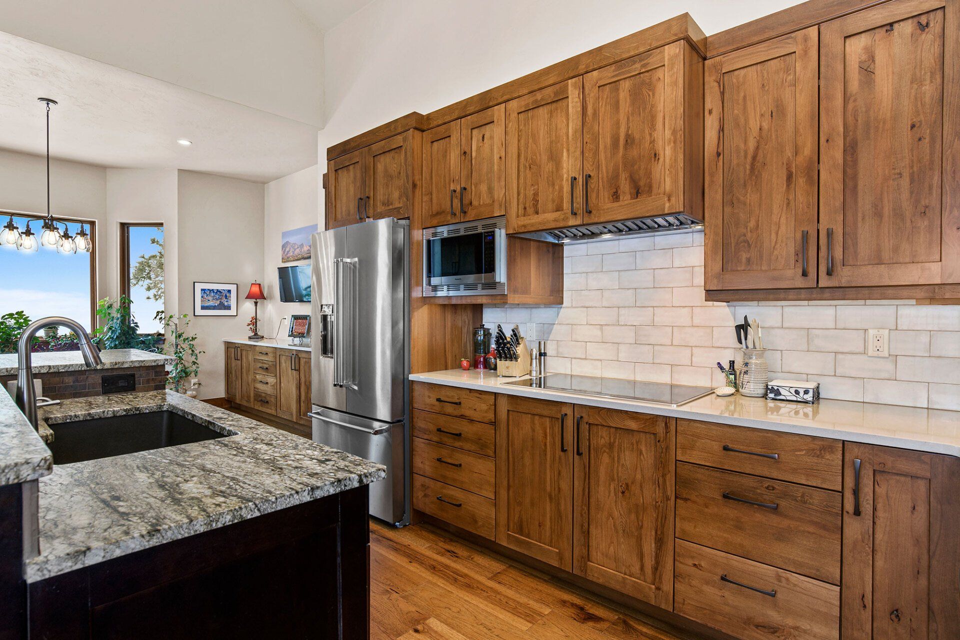 A kitchen with wooden cabinets , granite counter tops , stainless steel appliances and a sink.