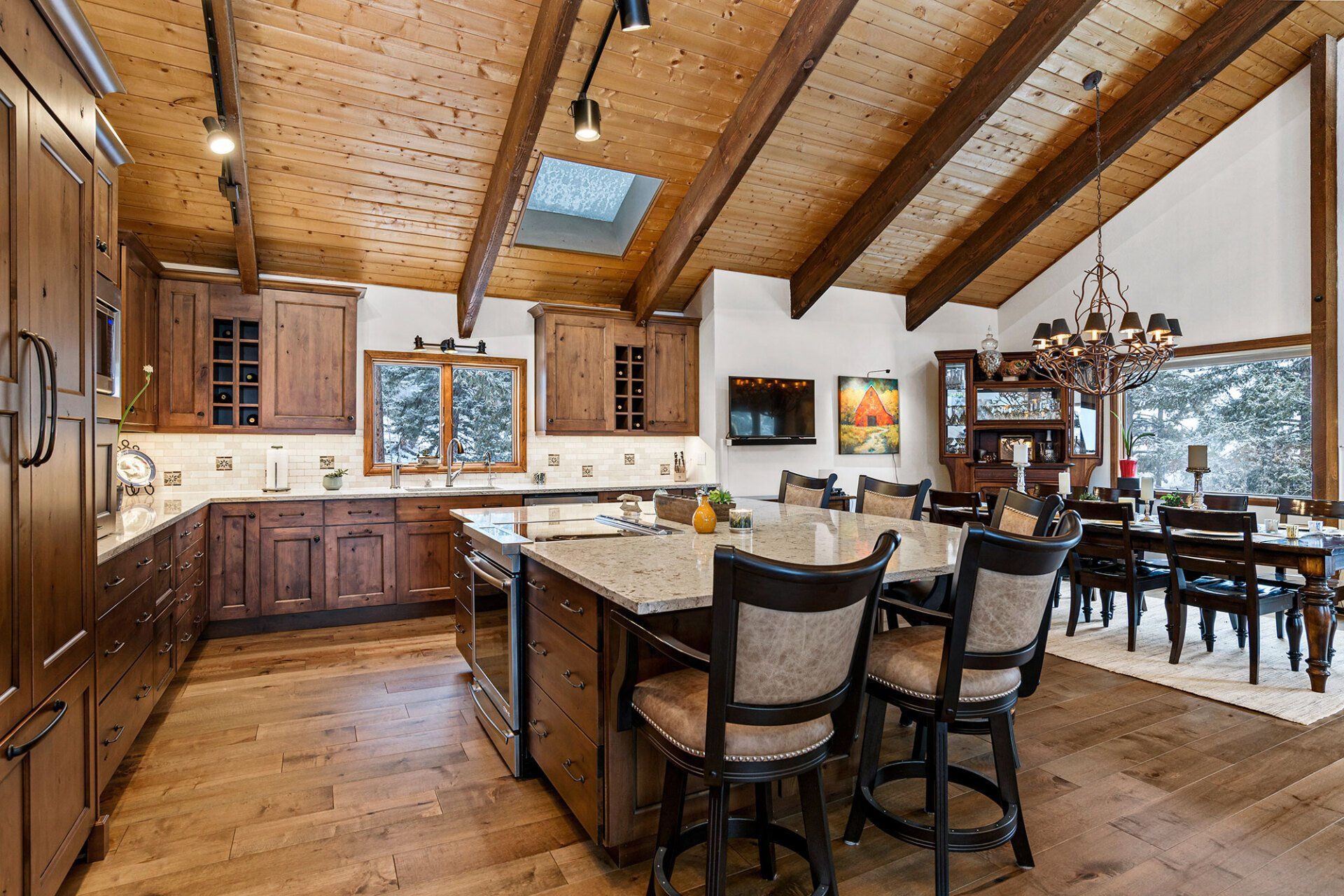 A kitchen with a large island in the middle and a dining room in the background.