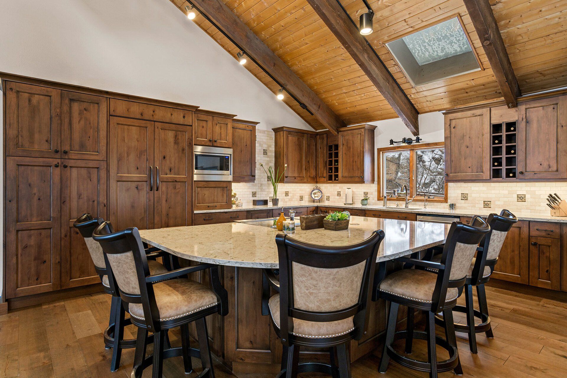 A kitchen with wooden cabinets and a large island with a table and chairs.