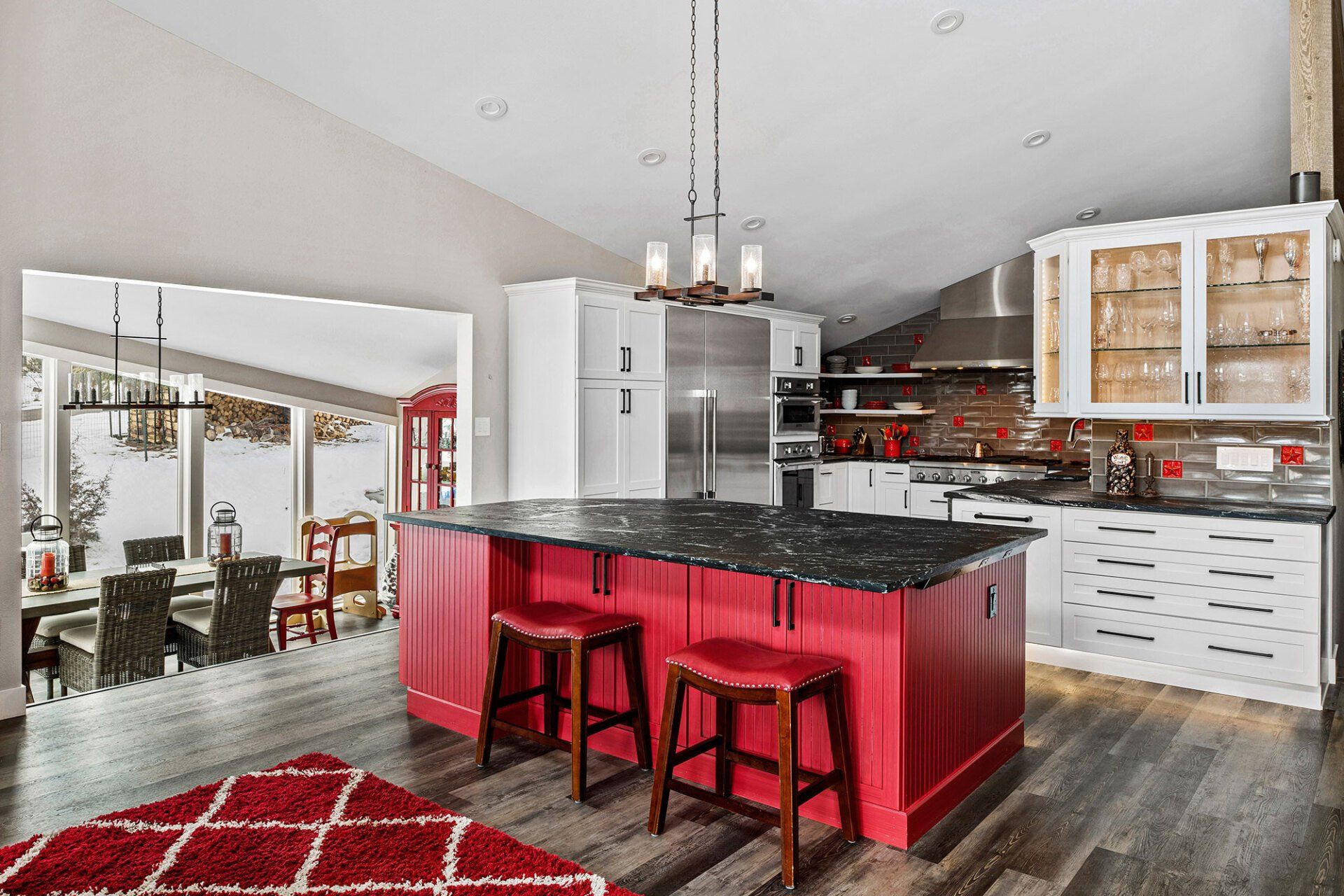 A kitchen with a large red island and stools.