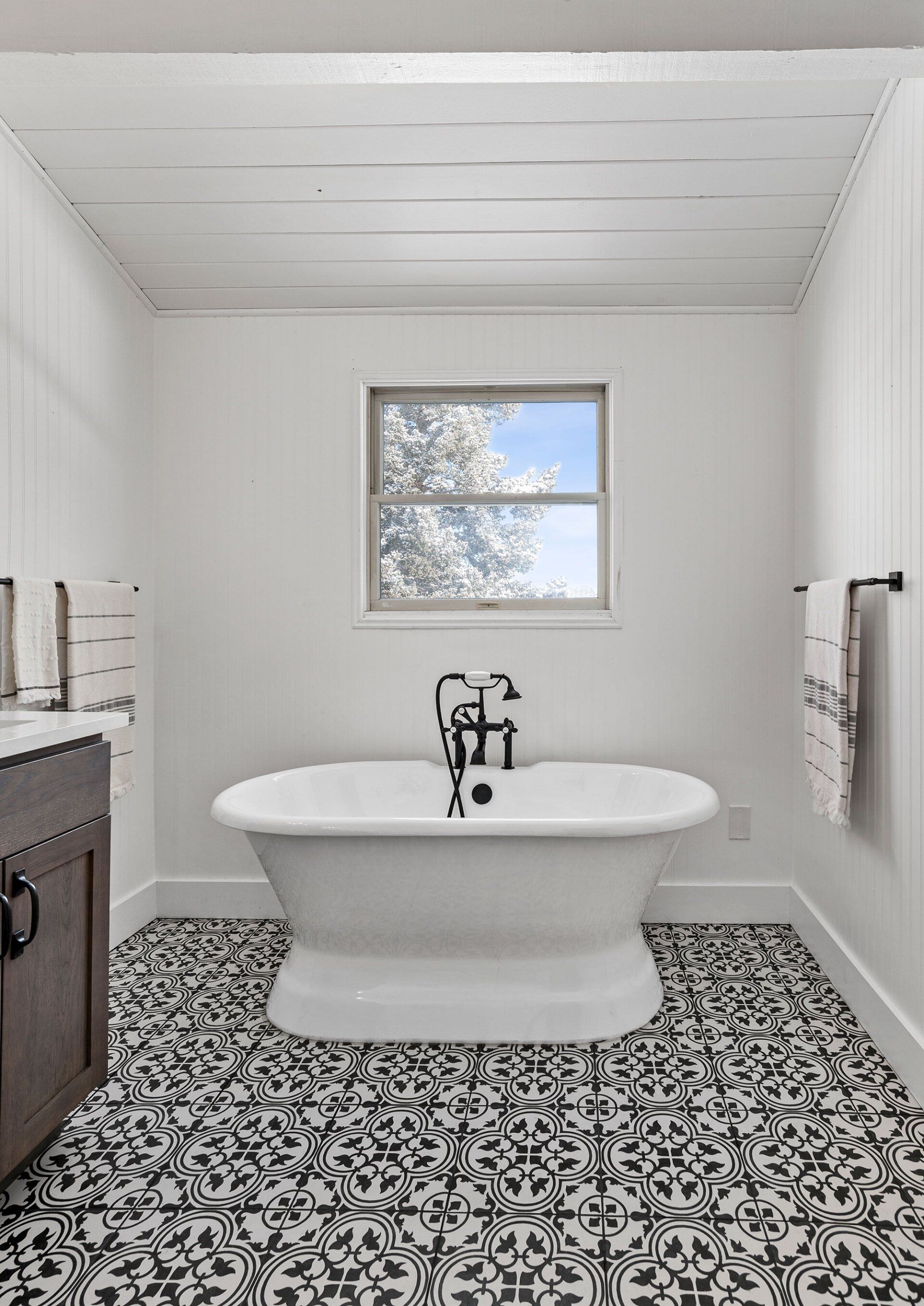A bathroom with a bathtub , sink , and window.