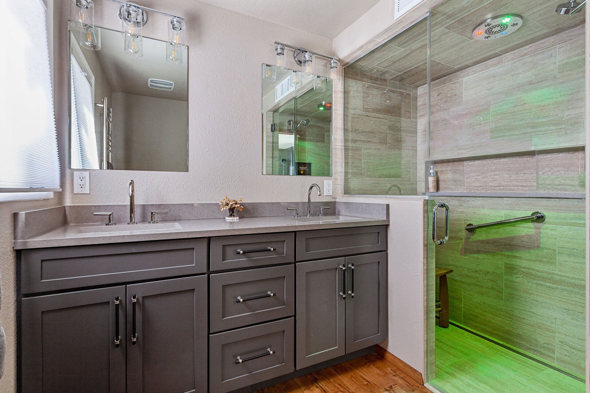 A bathroom with two sinks , a mirror and a walk in shower.