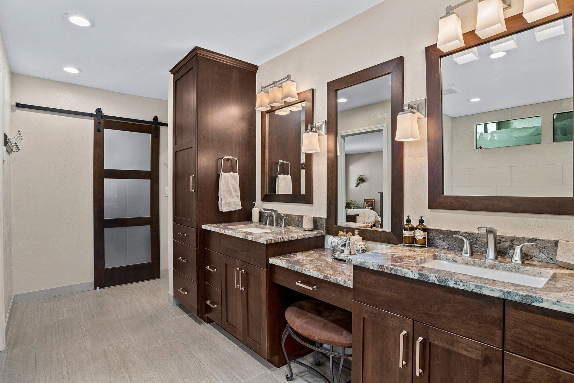 A bathroom with two sinks , two mirrors and a sliding barn door.