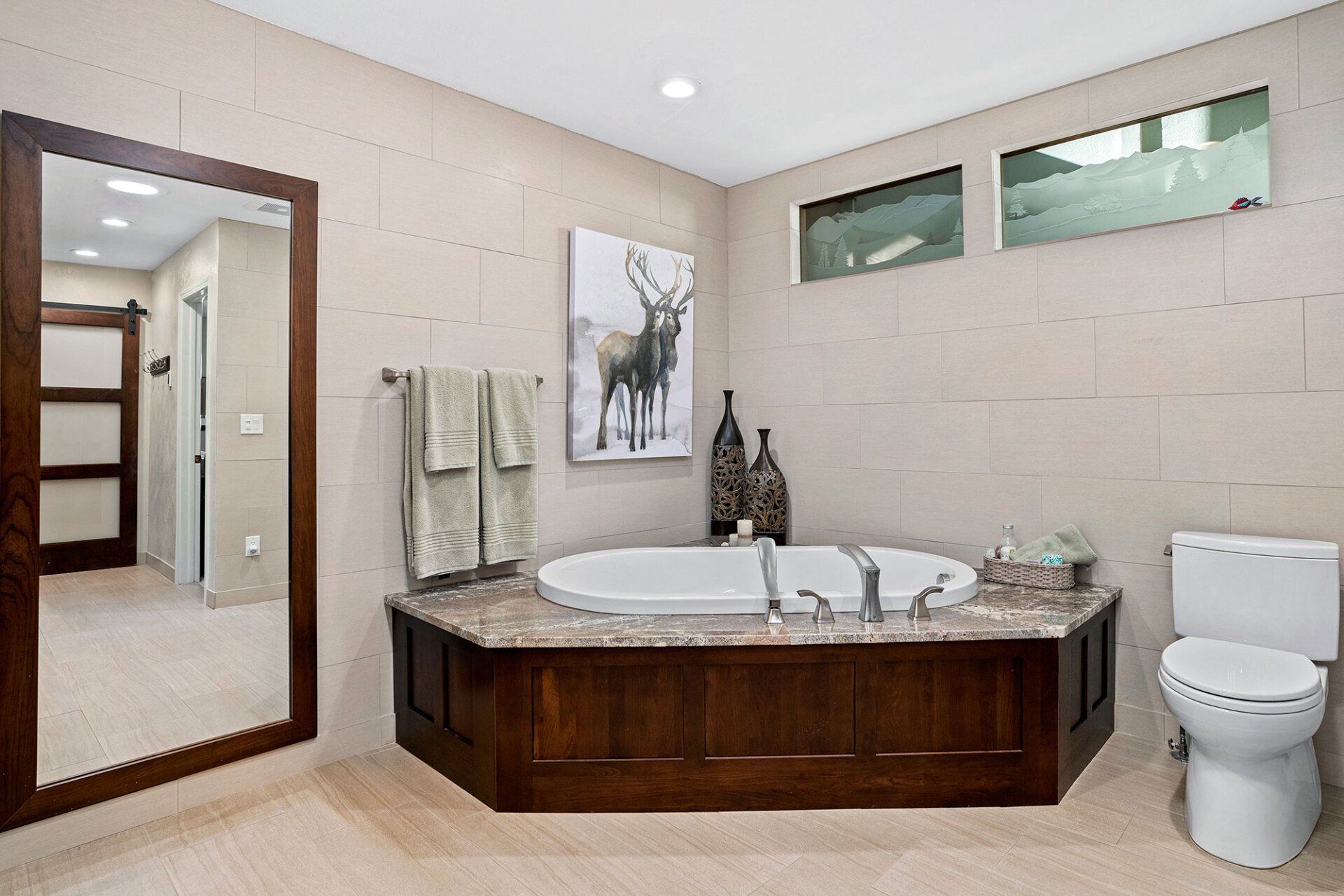 A bathroom with a large tub , toilet and mirror.