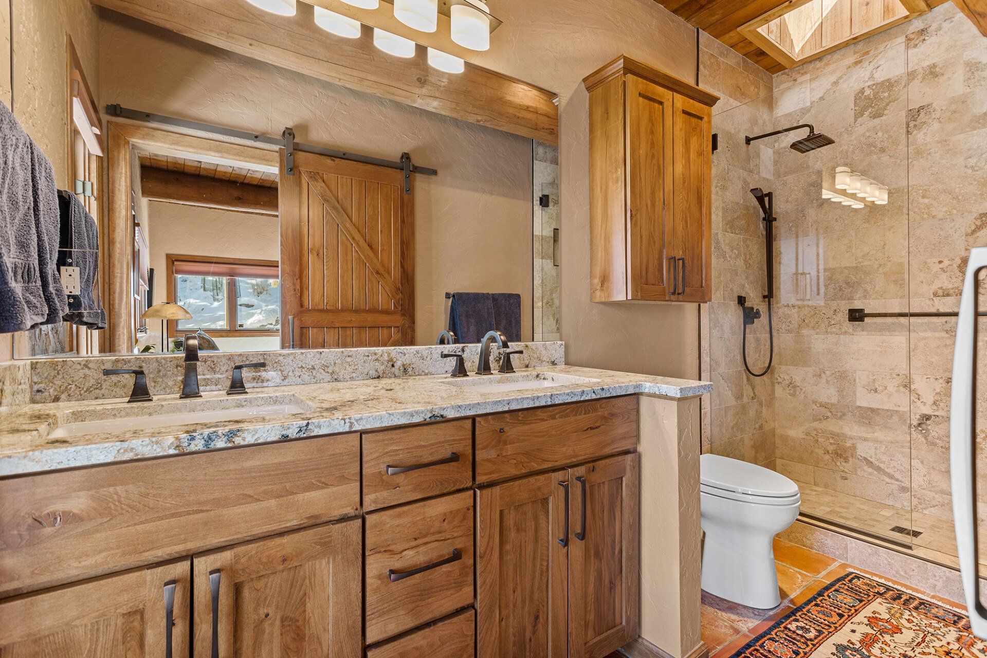 A bathroom with two sinks , a toilet and a shower.