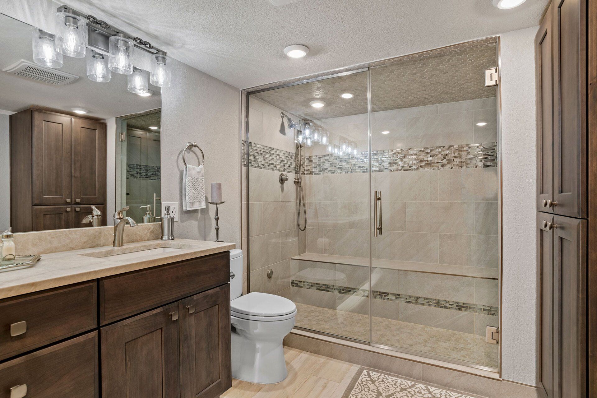 A bathroom with a toilet , sink , mirror and walk in shower.