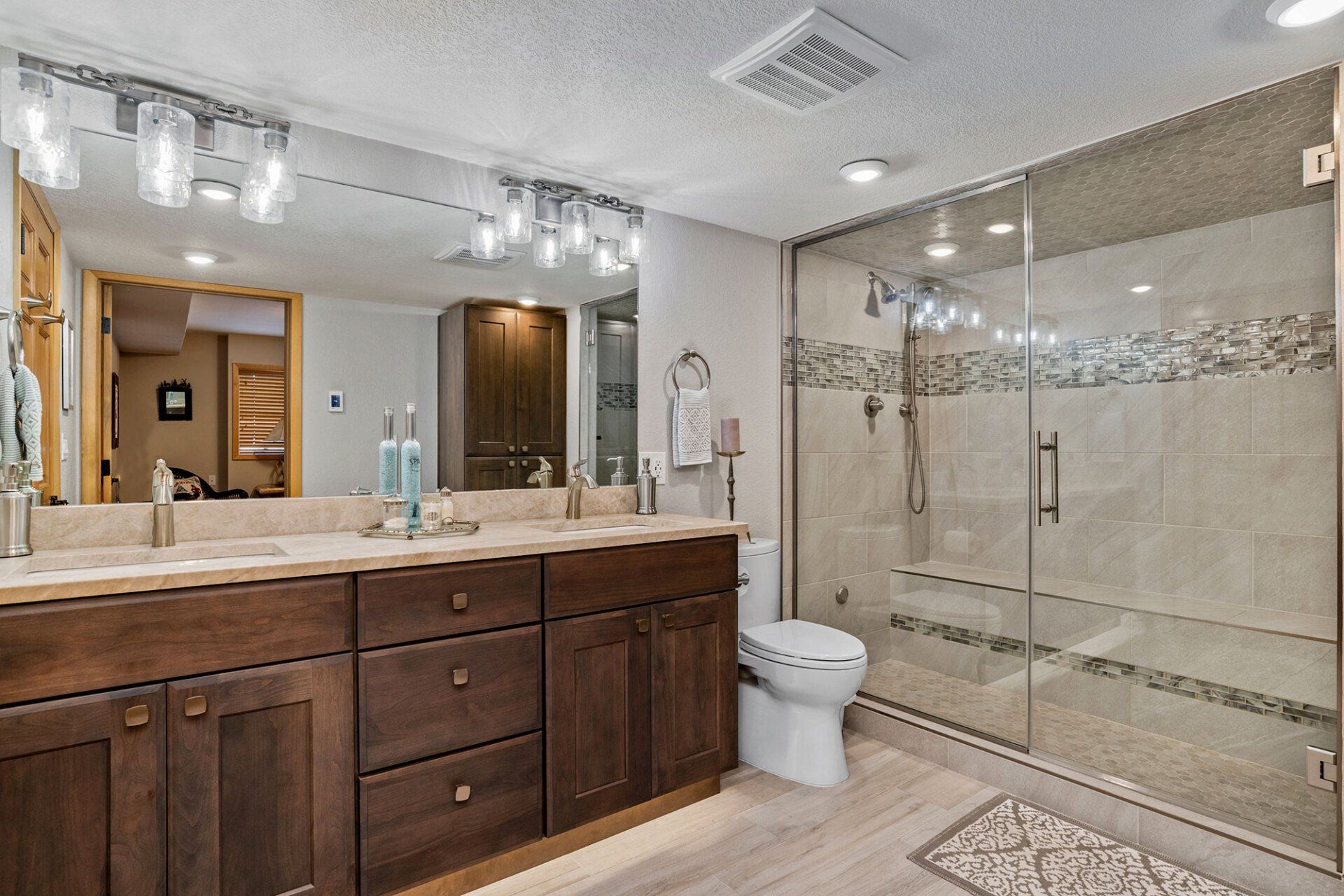 A bathroom with two sinks , a toilet , and a walk in shower.