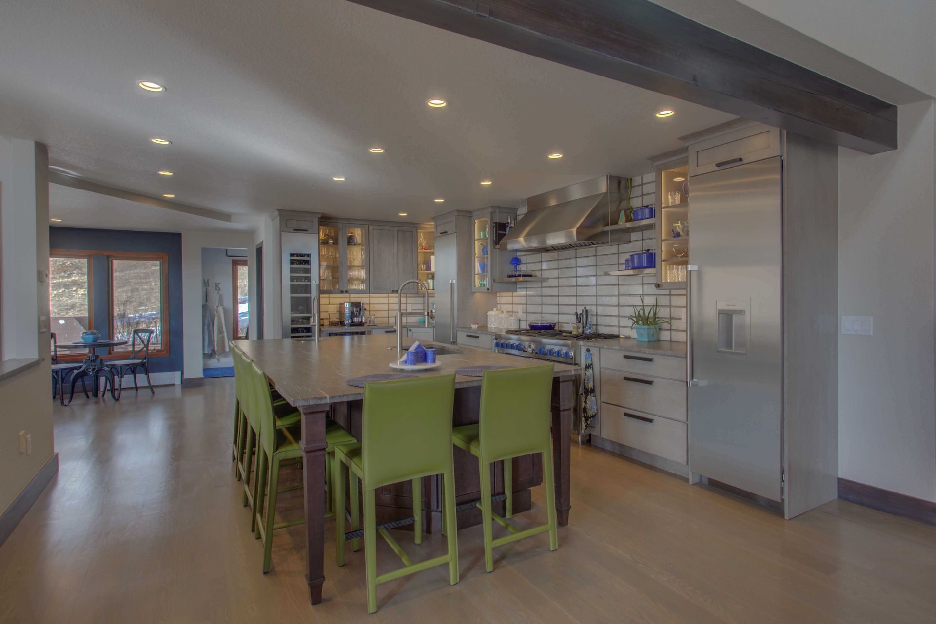 A large kitchen with a large island and green chairs.
