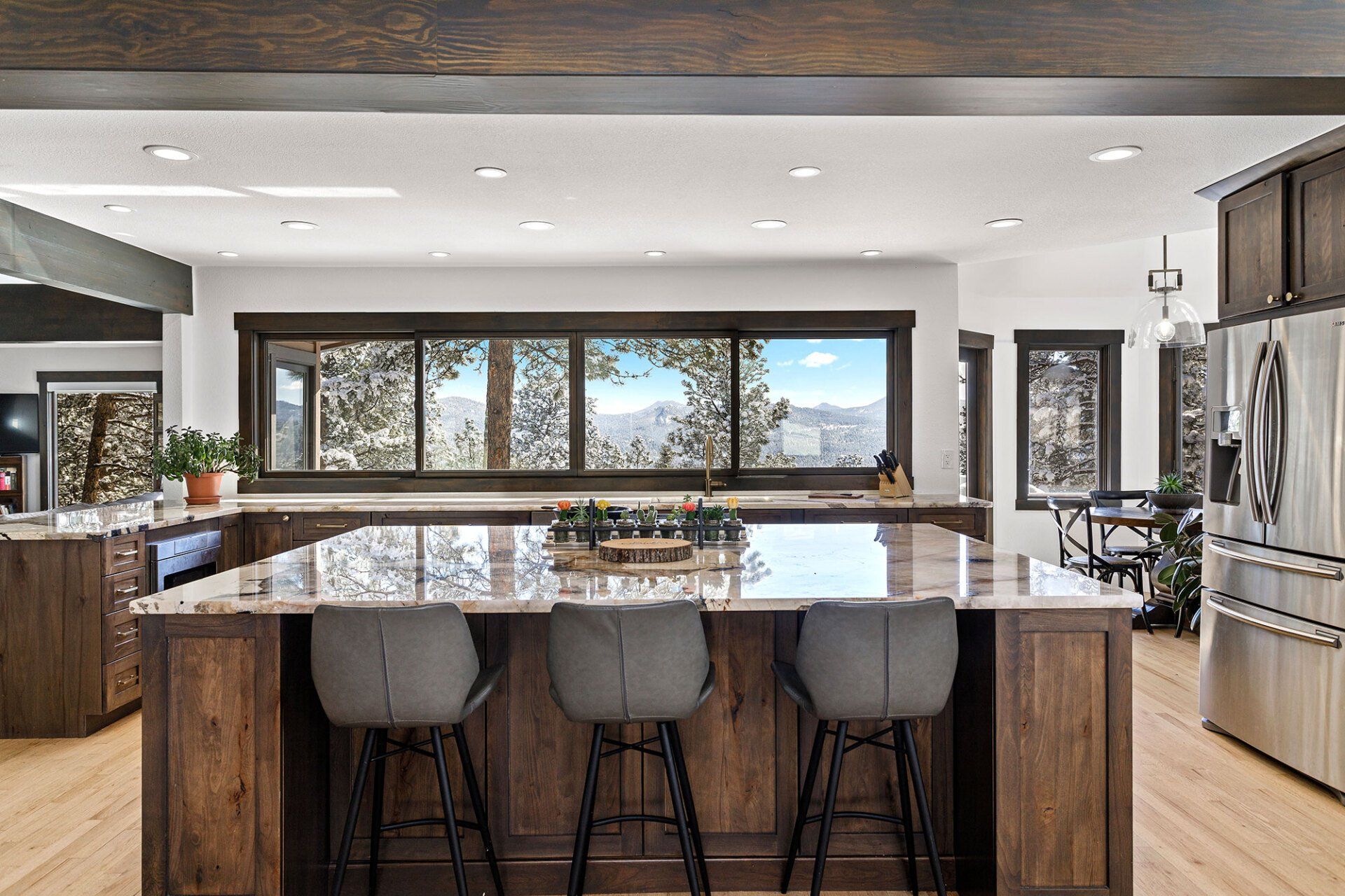 A kitchen with a large island and stools and a lot of windows.