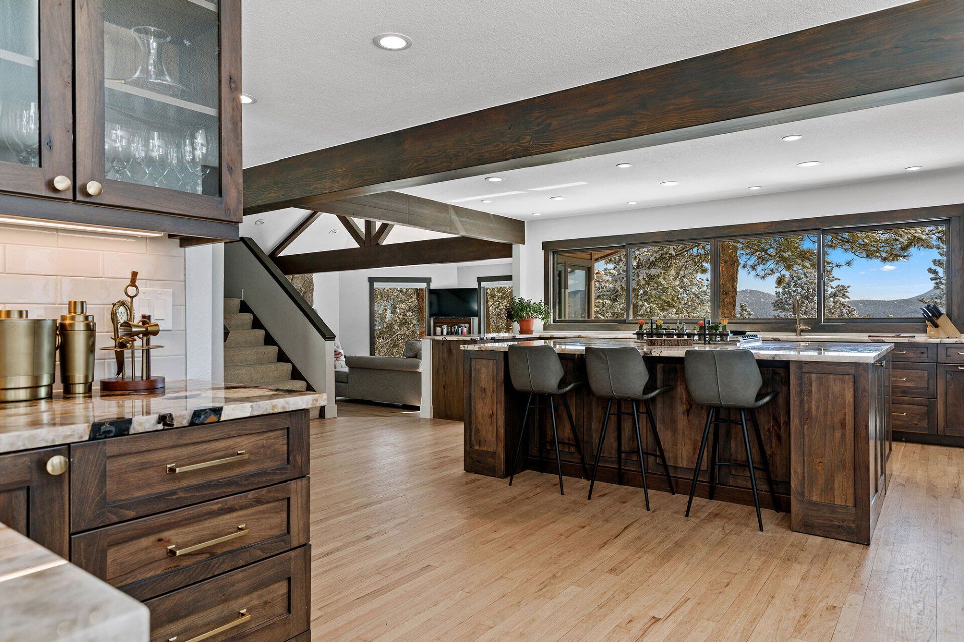 A kitchen with wooden cabinets , a large island , stools and a staircase.