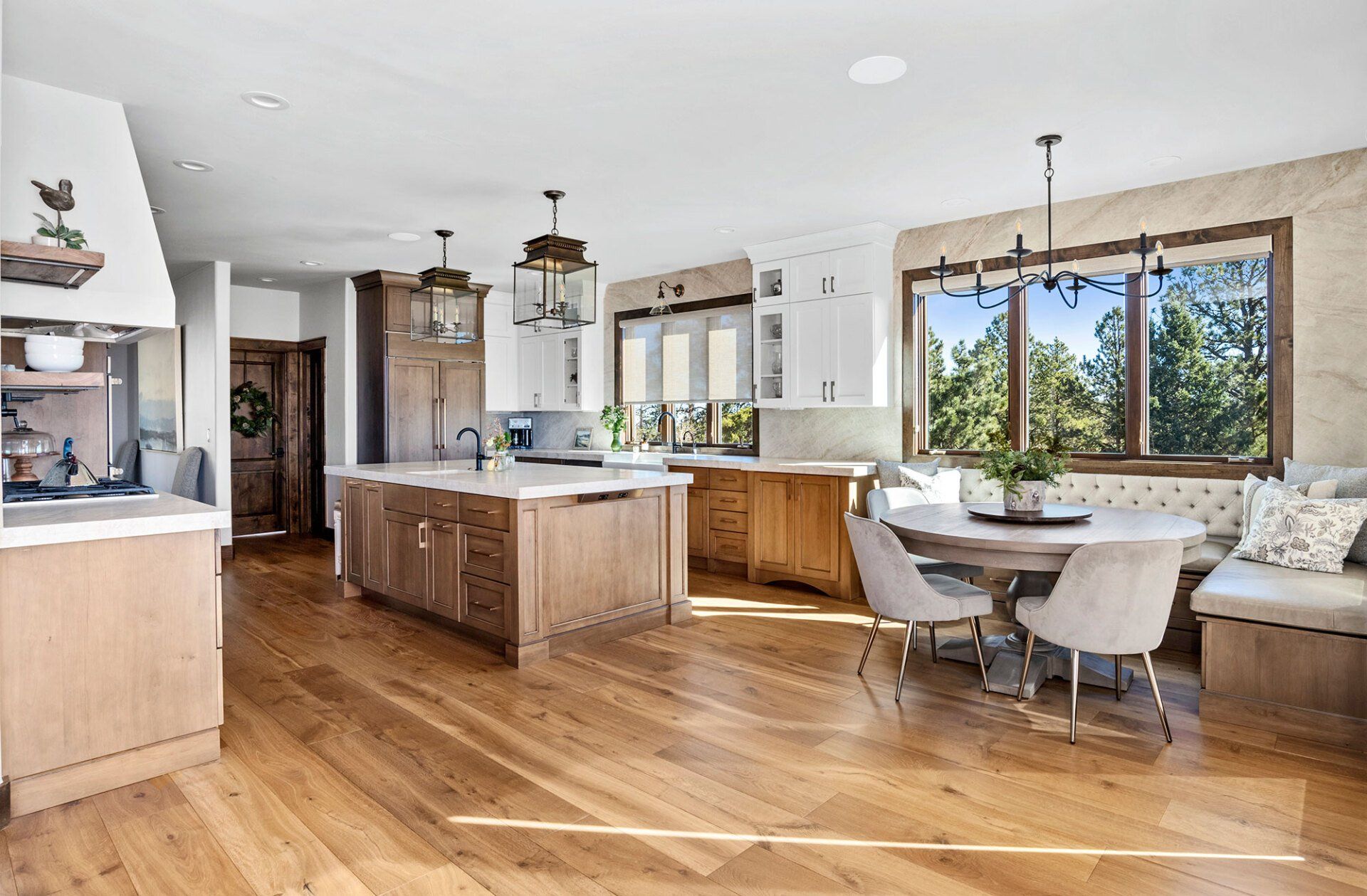 A kitchen with hardwood floors , a large island , a table and chairs.