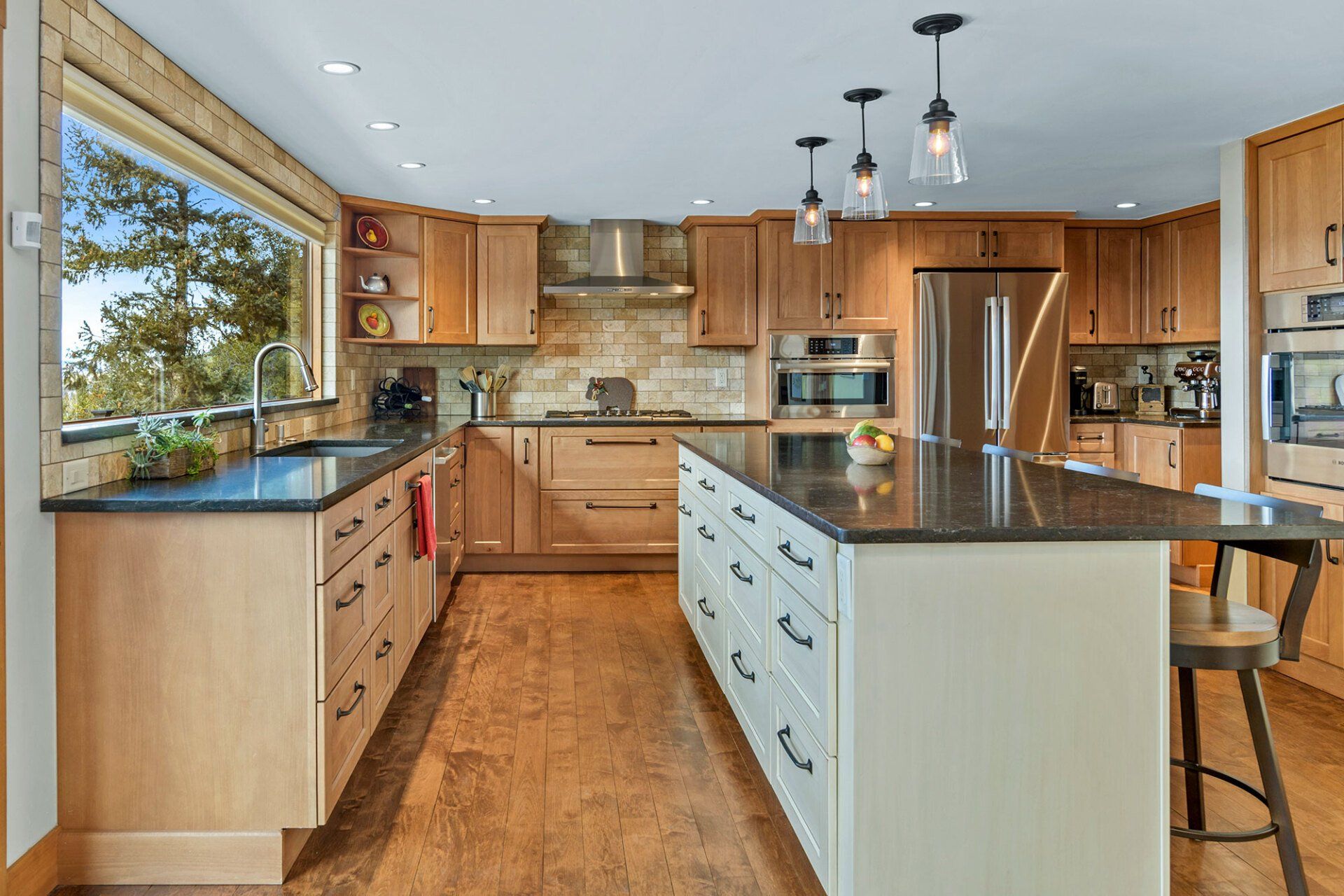 A kitchen with wooden cabinets , granite counter tops , stainless steel appliances and a large island.