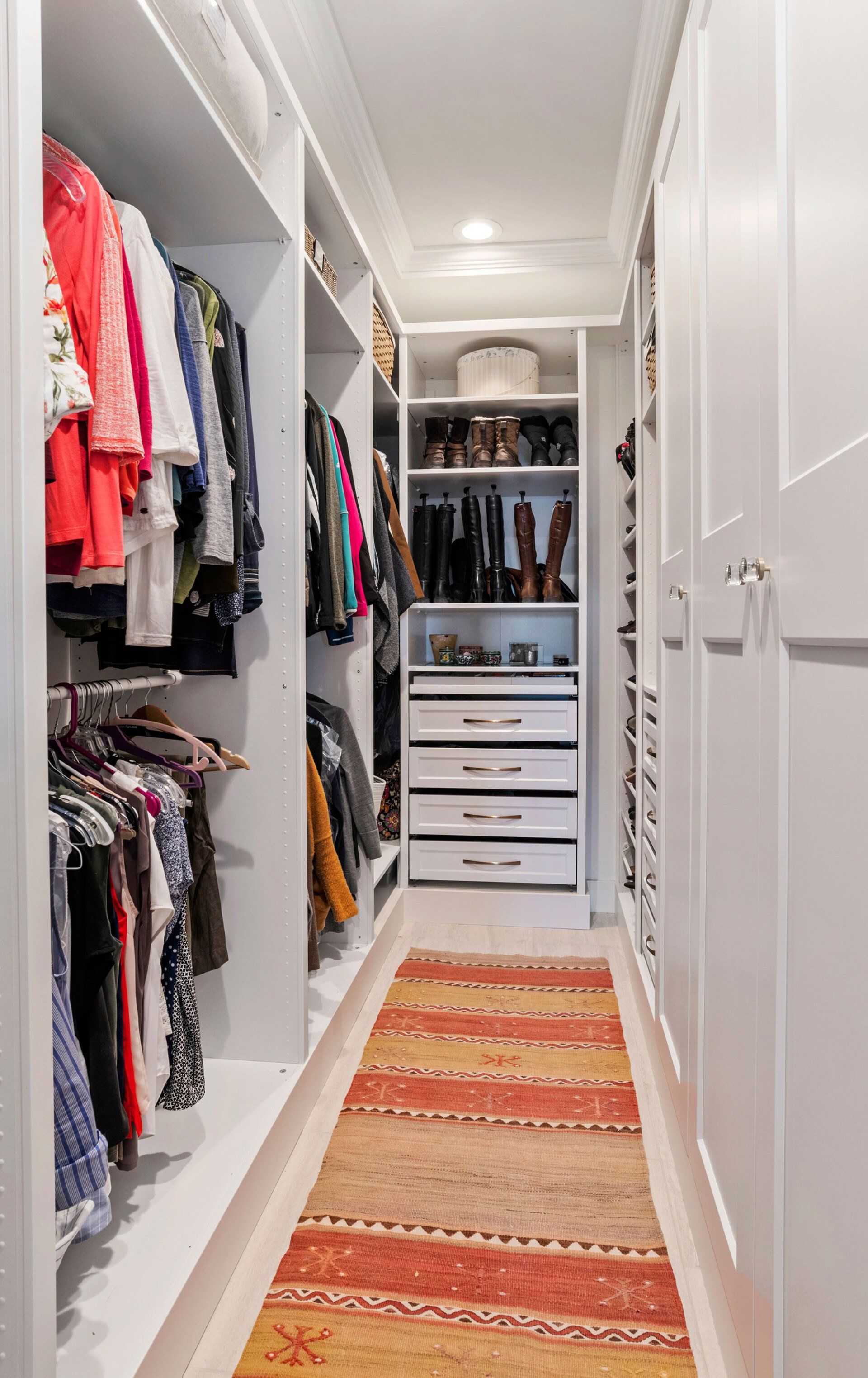 A walk in closet filled with lots of clothes and a rug.