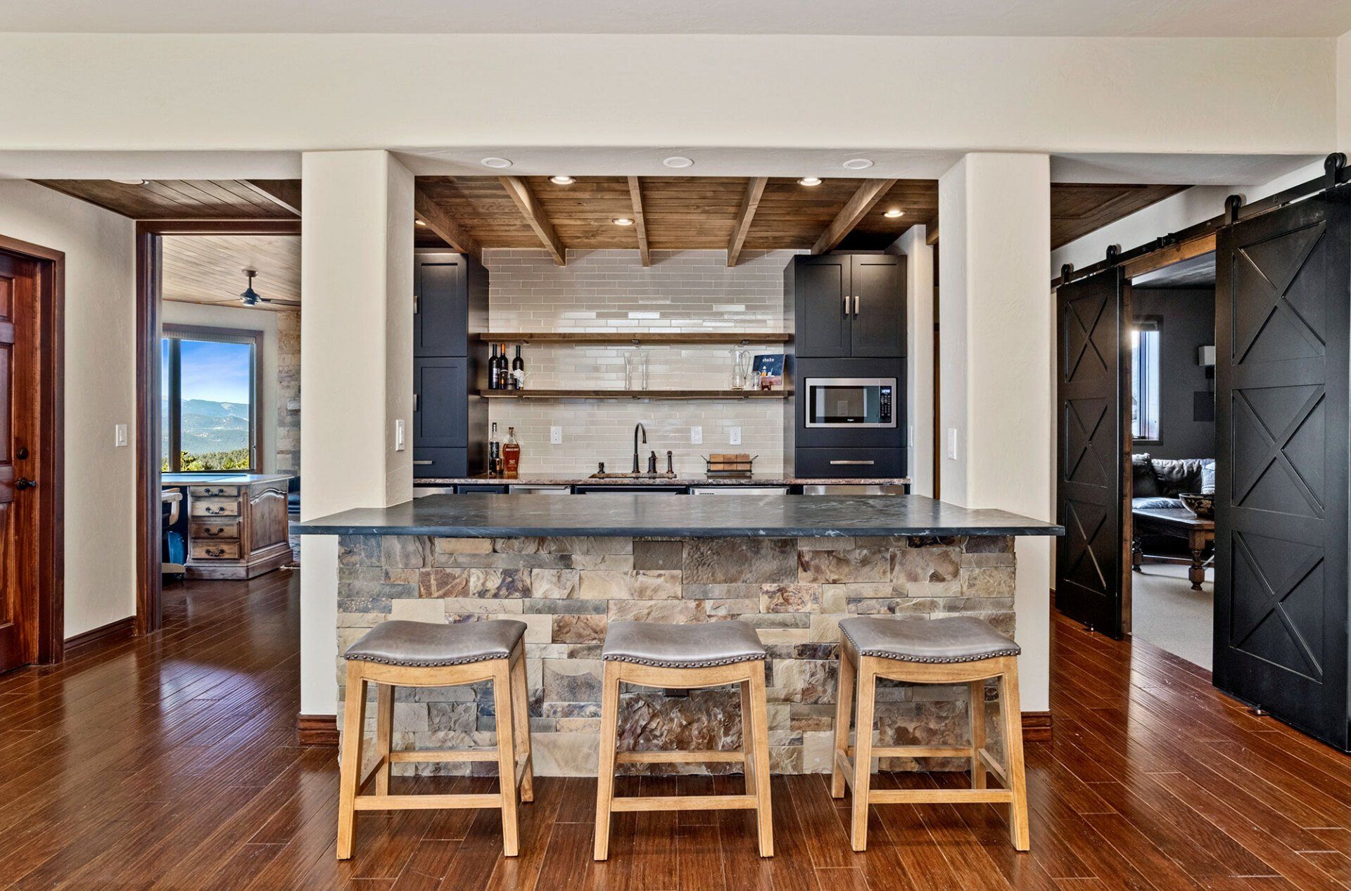 A kitchen with a stone counter top and wooden stools.