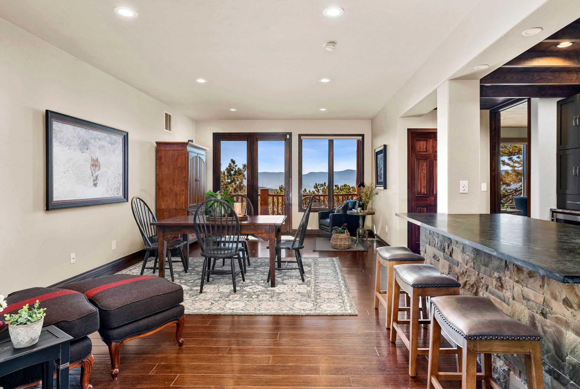 A living room with hardwood floors , a table and chairs , and a bar.
