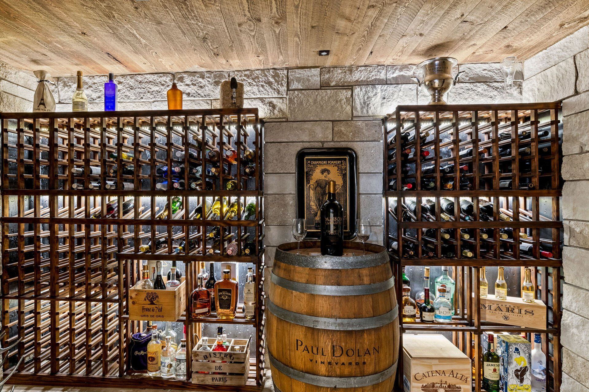 A wine cellar filled with lots of wine bottles and a wooden barrel.