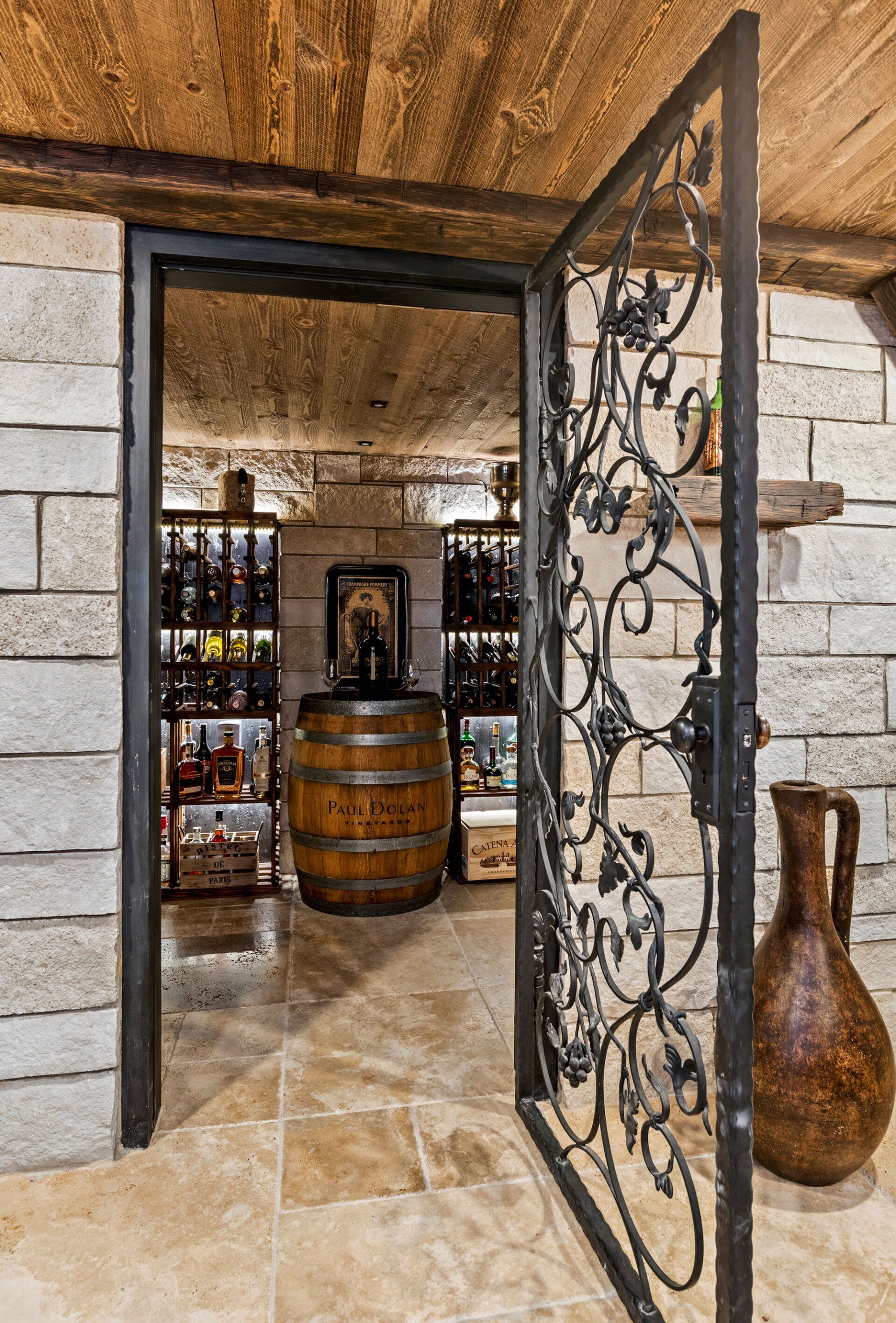 A wine cellar with a wrought iron gate and a wooden barrel.