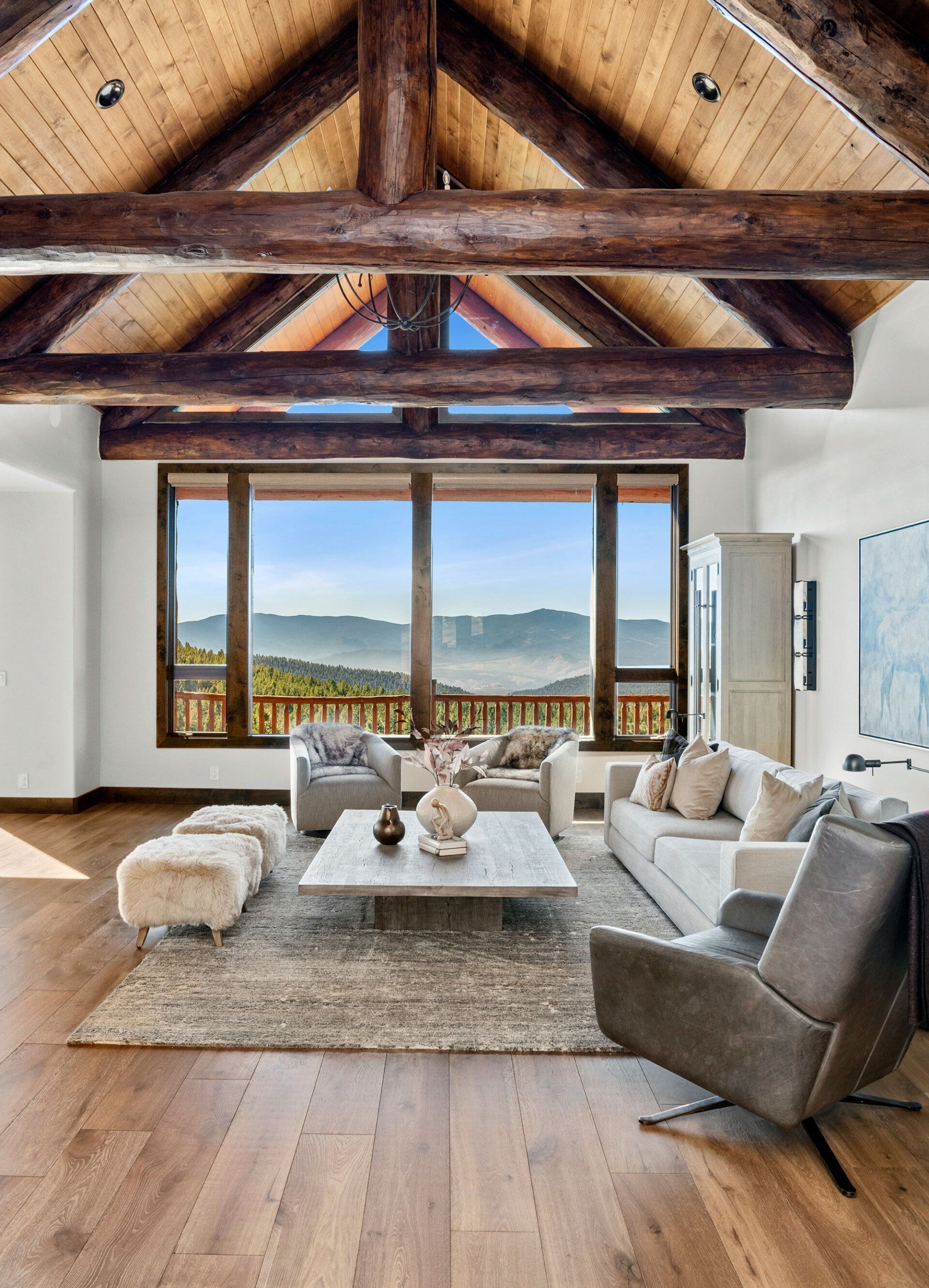 A living room with a couch , chairs , coffee table and large windows.
