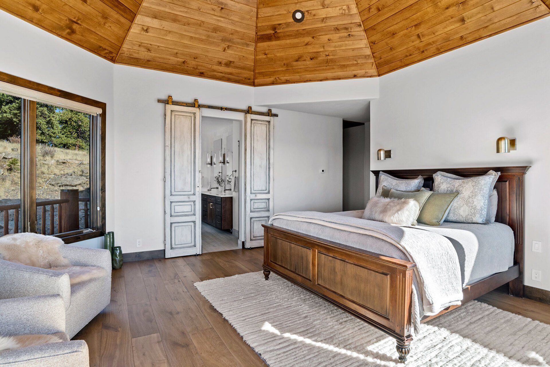 A bedroom with a bed , chair , and sliding barn doors.