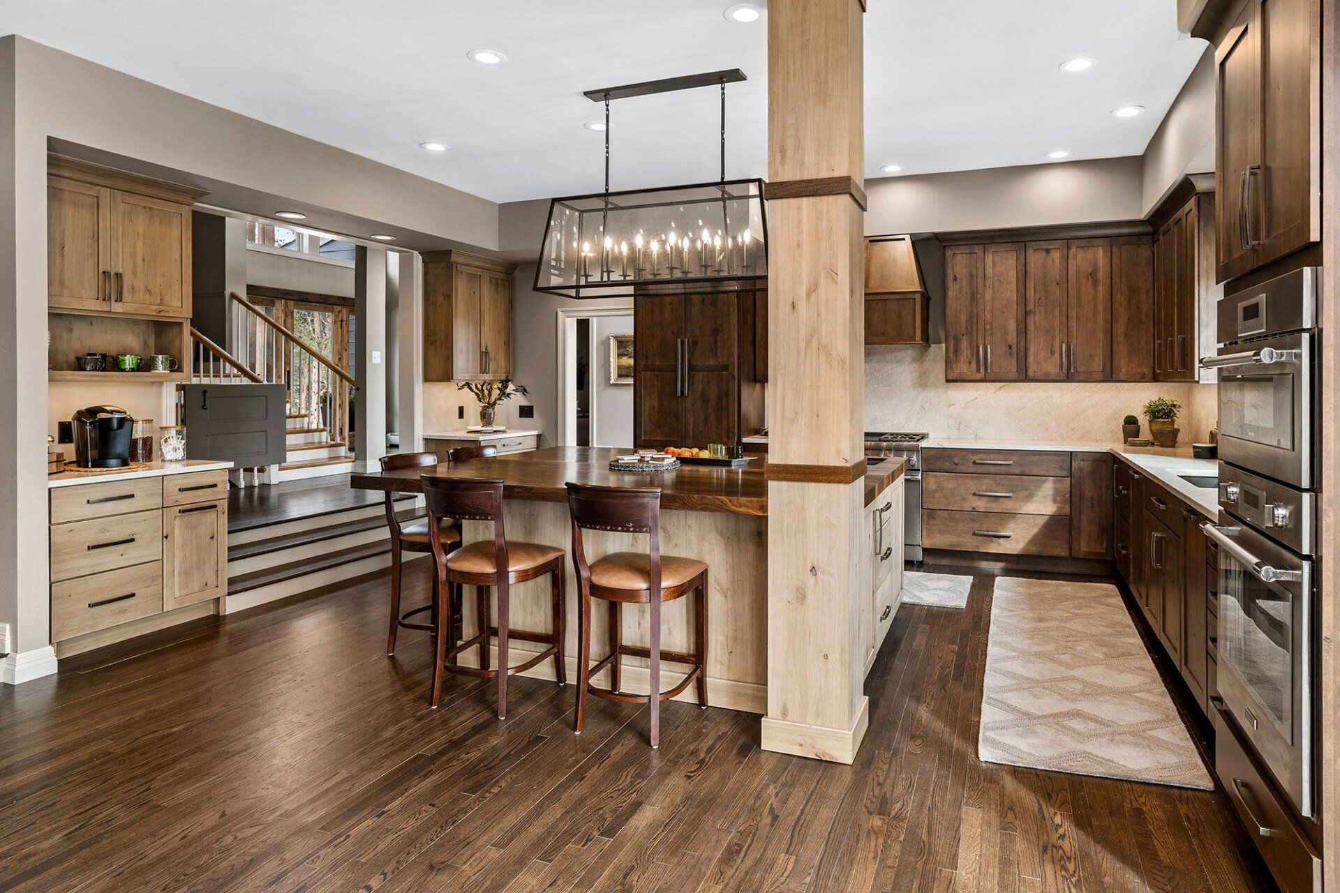 A kitchen with wooden cabinets and stools and a large island.
