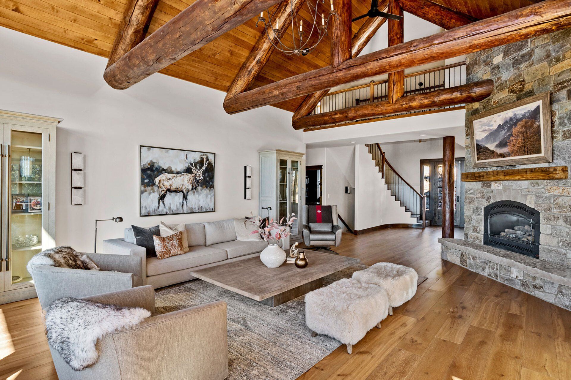 A living room with a couch , chairs , ottomans and a fireplace.