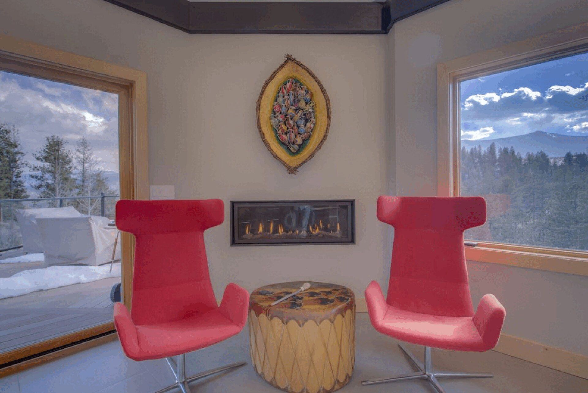 A living room with two red chairs and a fireplace.