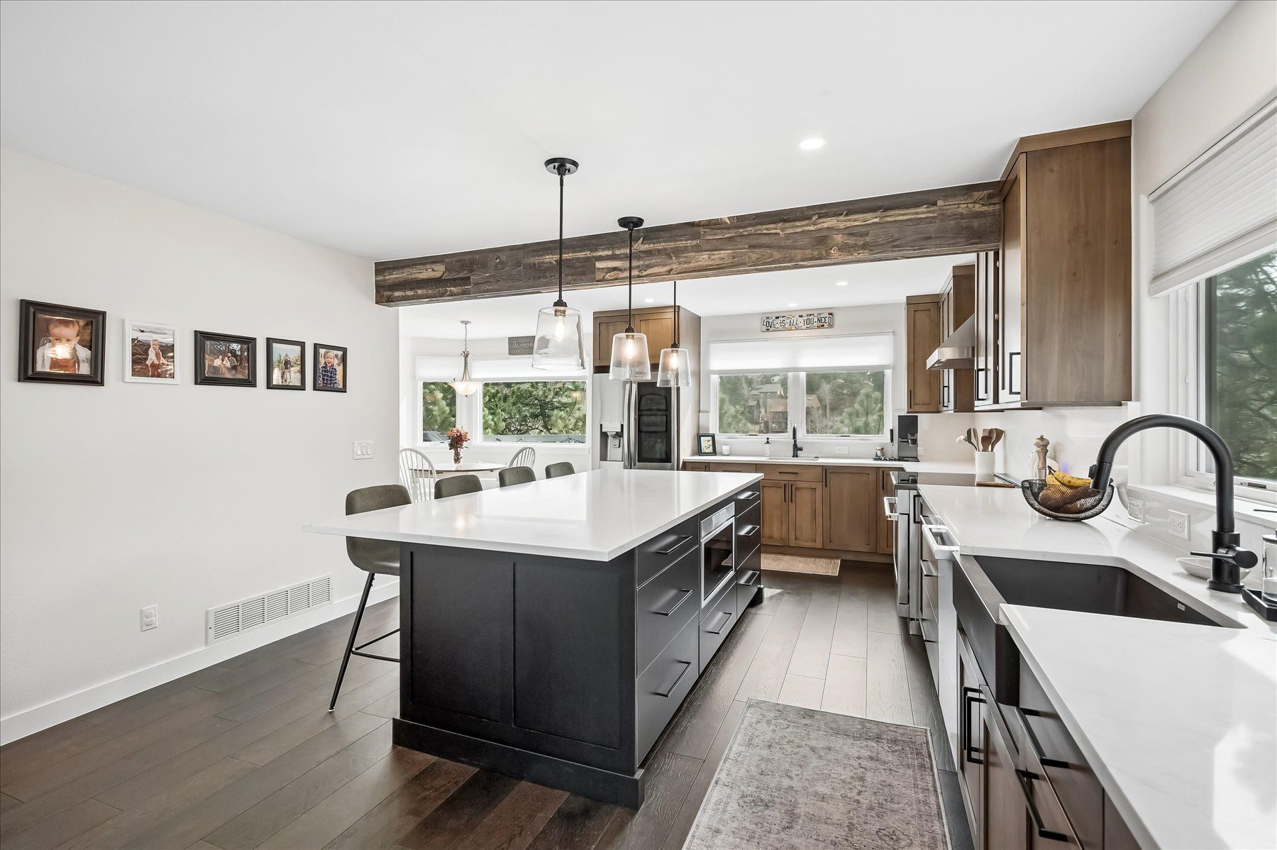 Modern kitchen with white cabinets, black island, pendant lights, and large windows