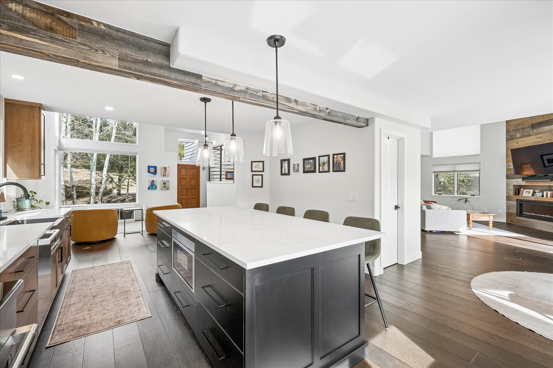 Modern kitchen with large island, pendant lights, white cabinets, and open view into adjoining living area