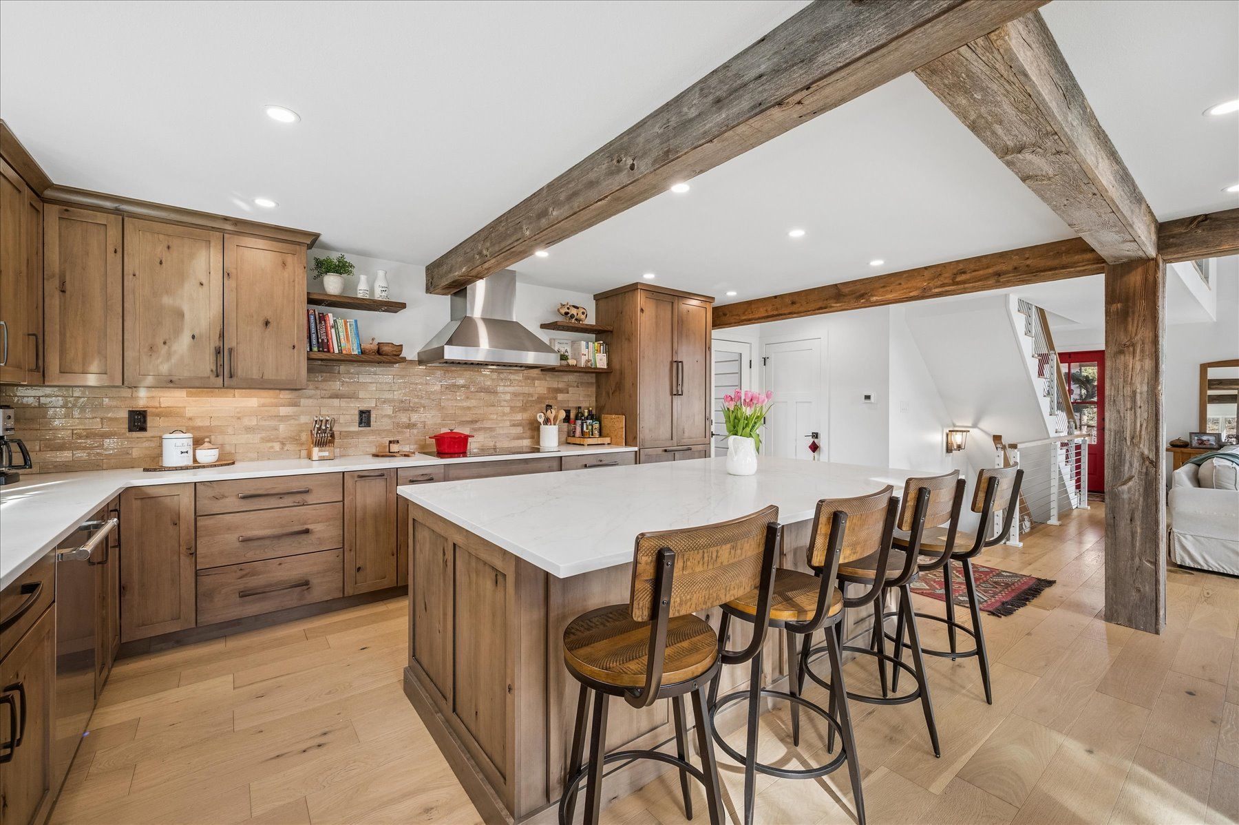 Modern kitchen with wood beams, large island, stools, and white cabinetry
