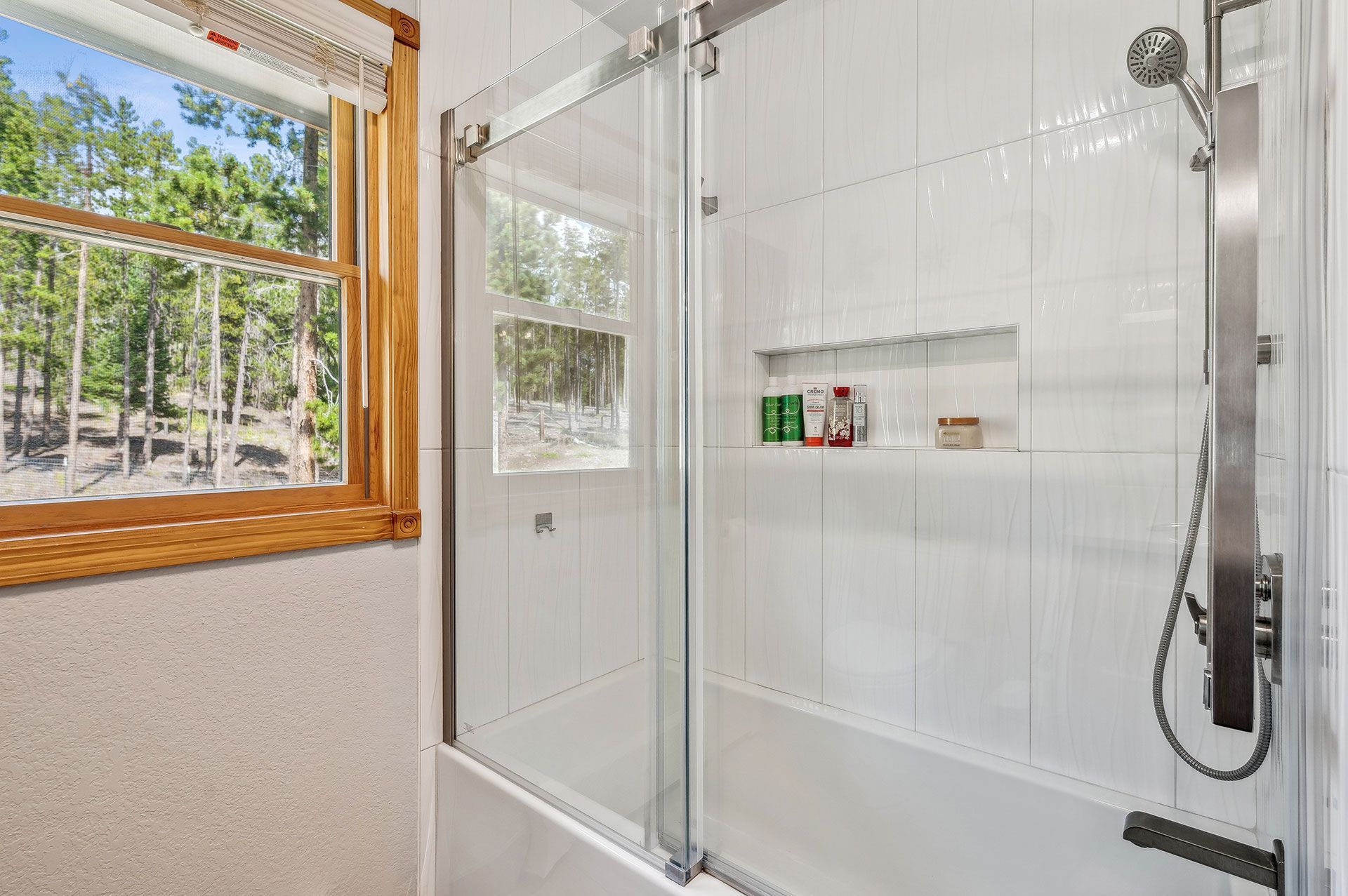 A bathroom with a sliding glass shower door and a window.