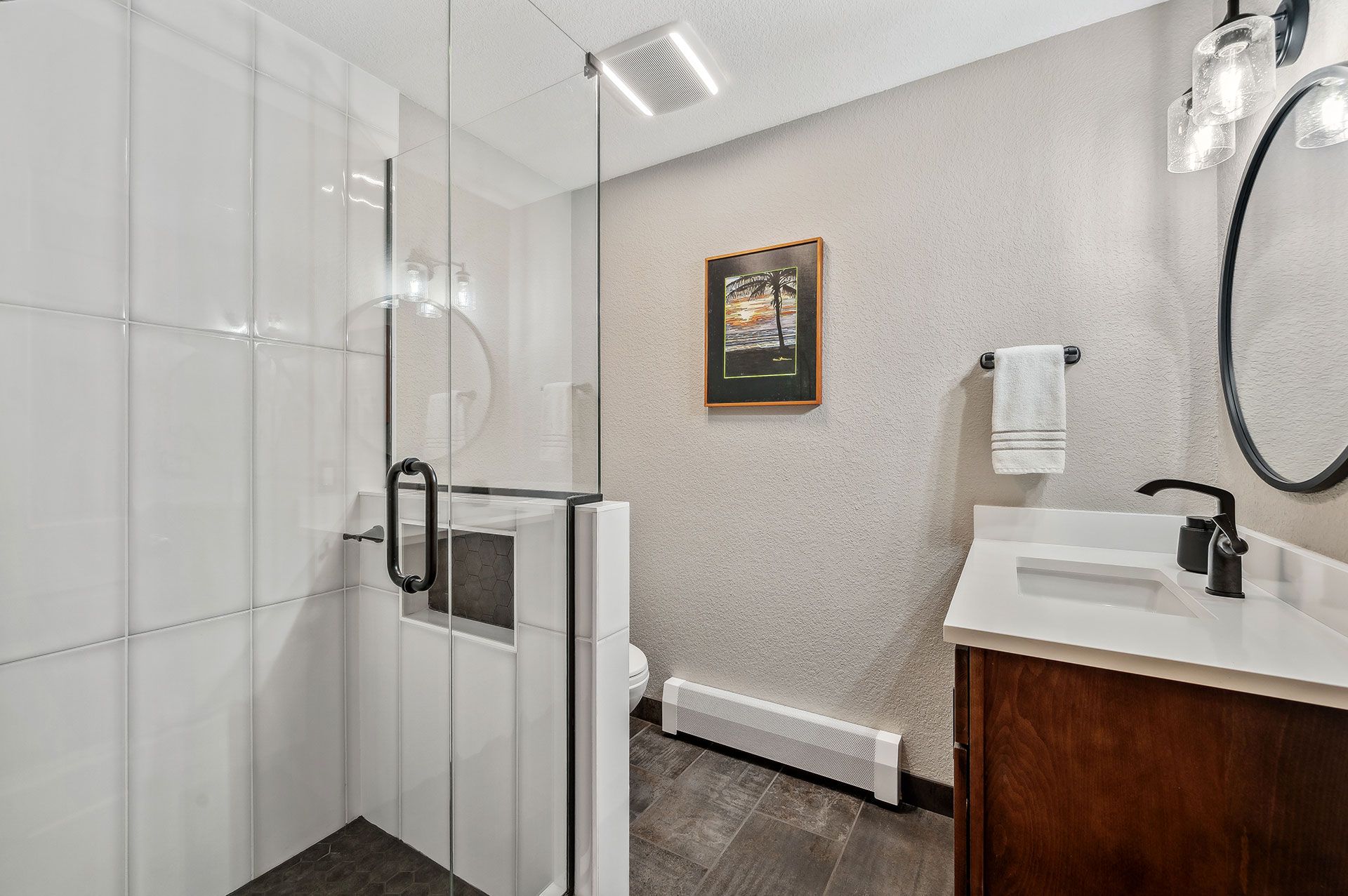 A bathroom with a walk in shower , sink and mirror.