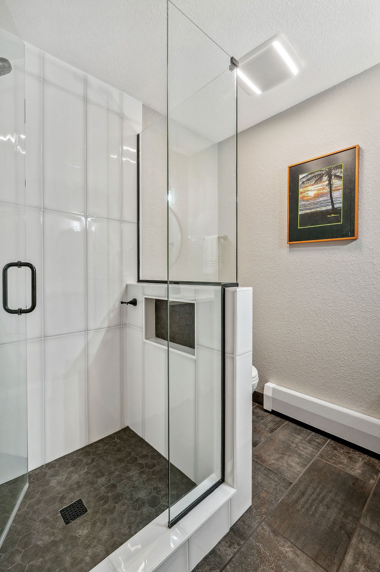 A bathroom with a walk in shower and a picture on the wall.