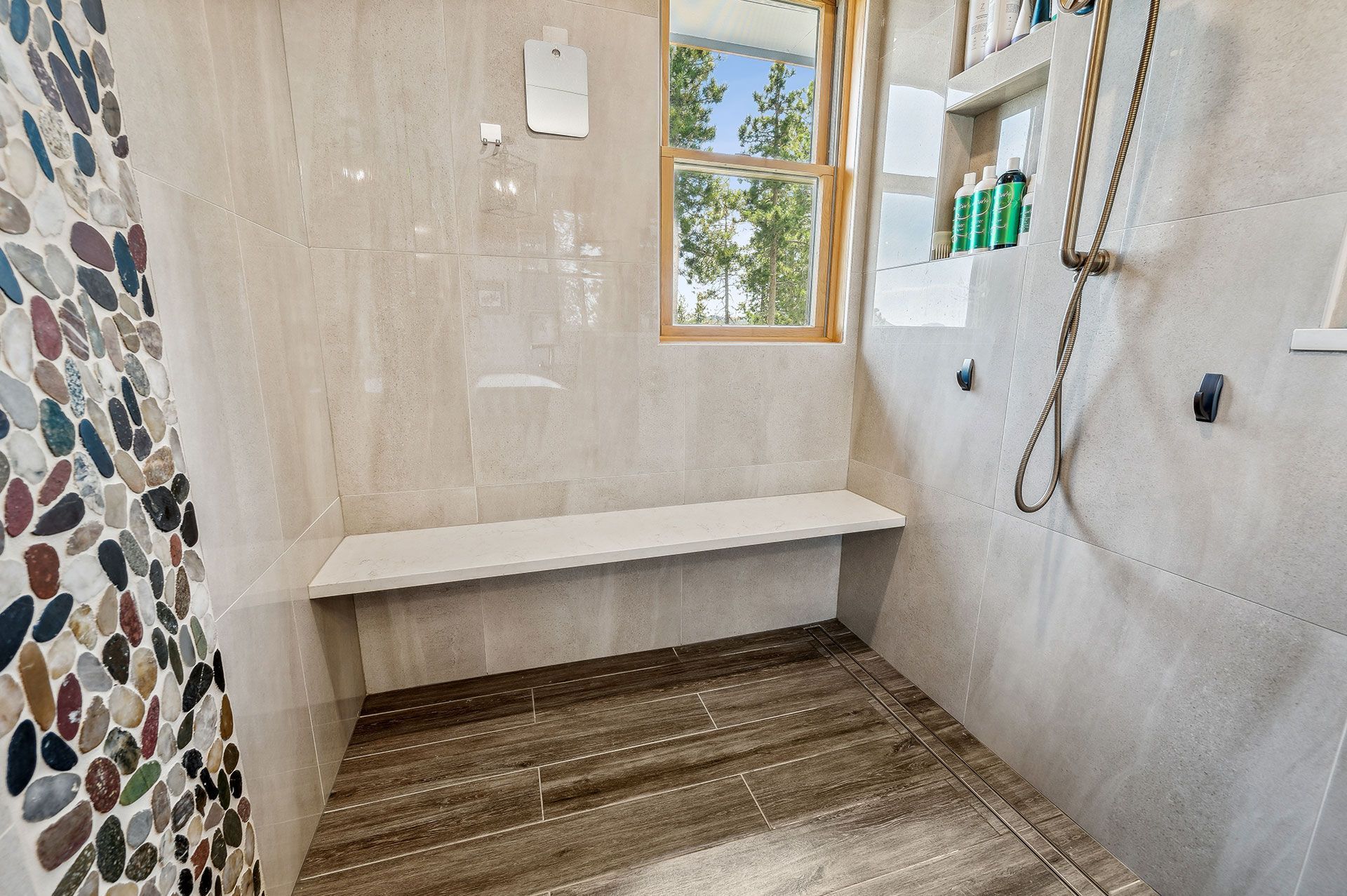 A bathroom with a bench in the shower and a window.